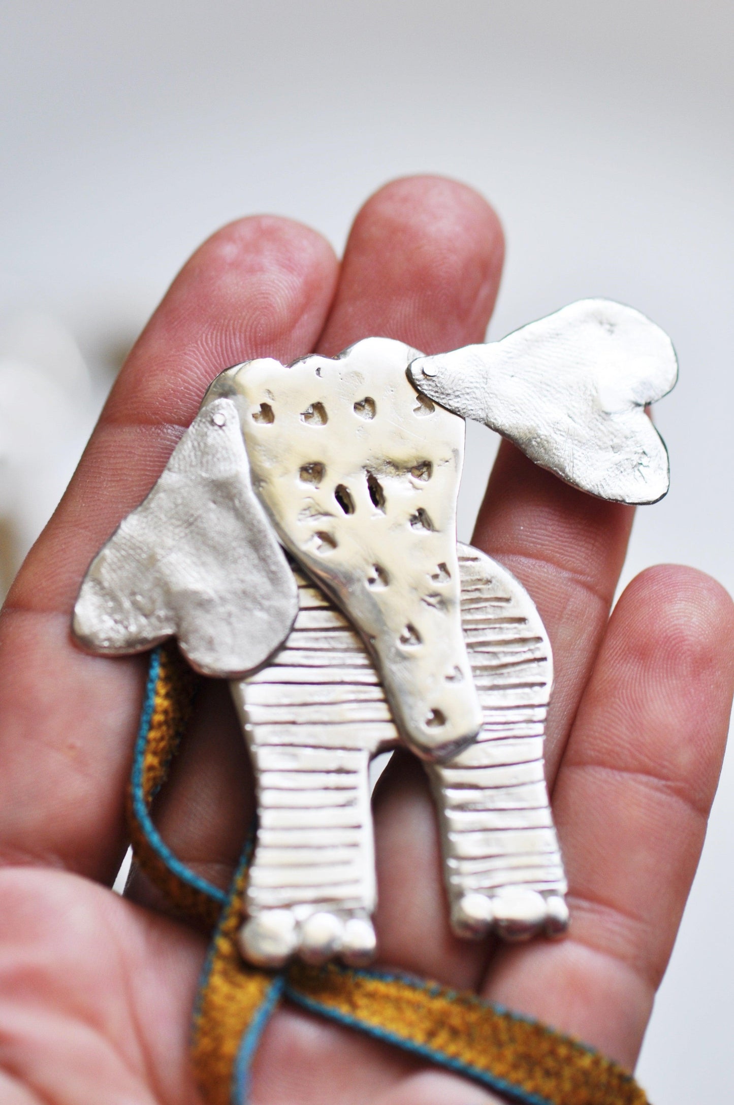 a person holding a small elephant brooch in their hand