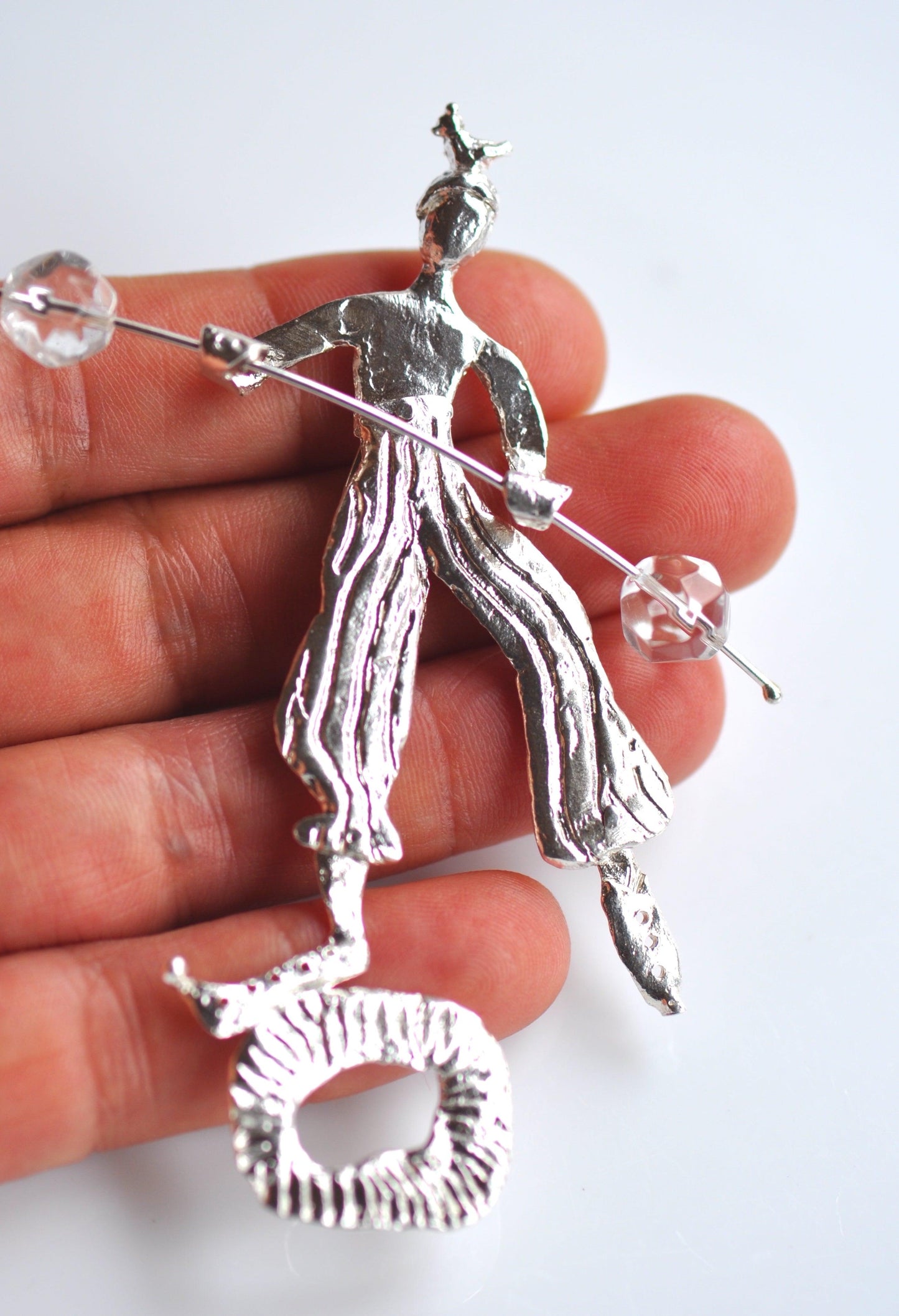 a person is holding a silver brooch