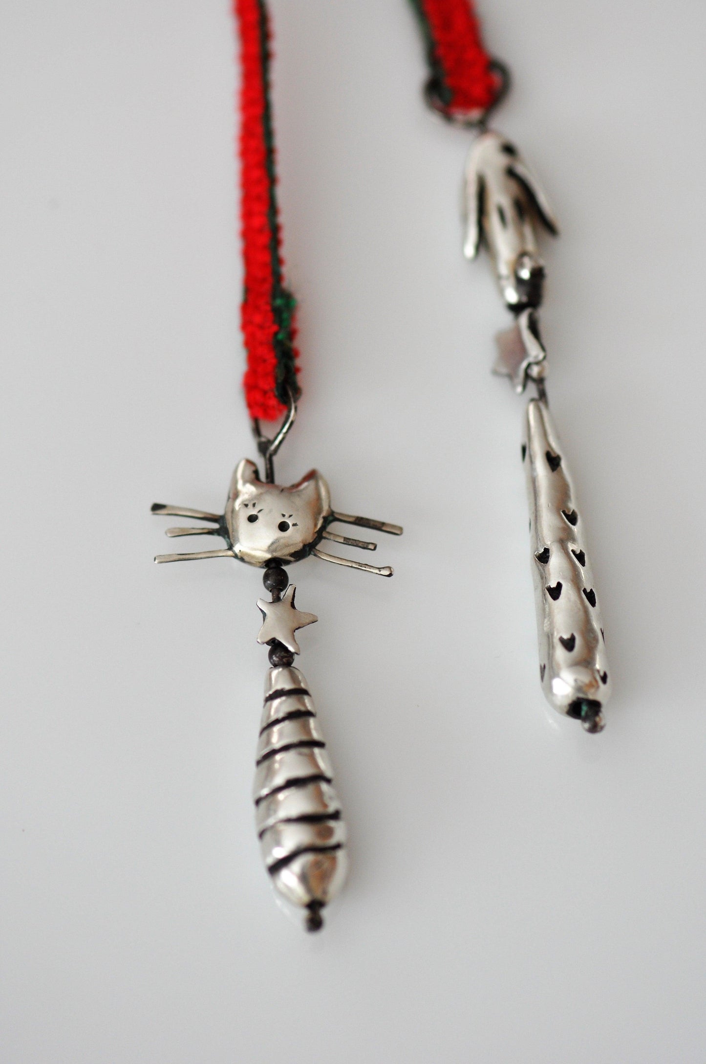 a silver cat necklace with a red cord