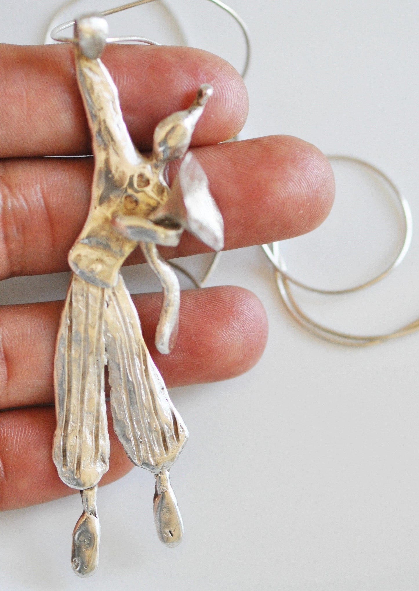 a person holding a silver bird ornament in their hand