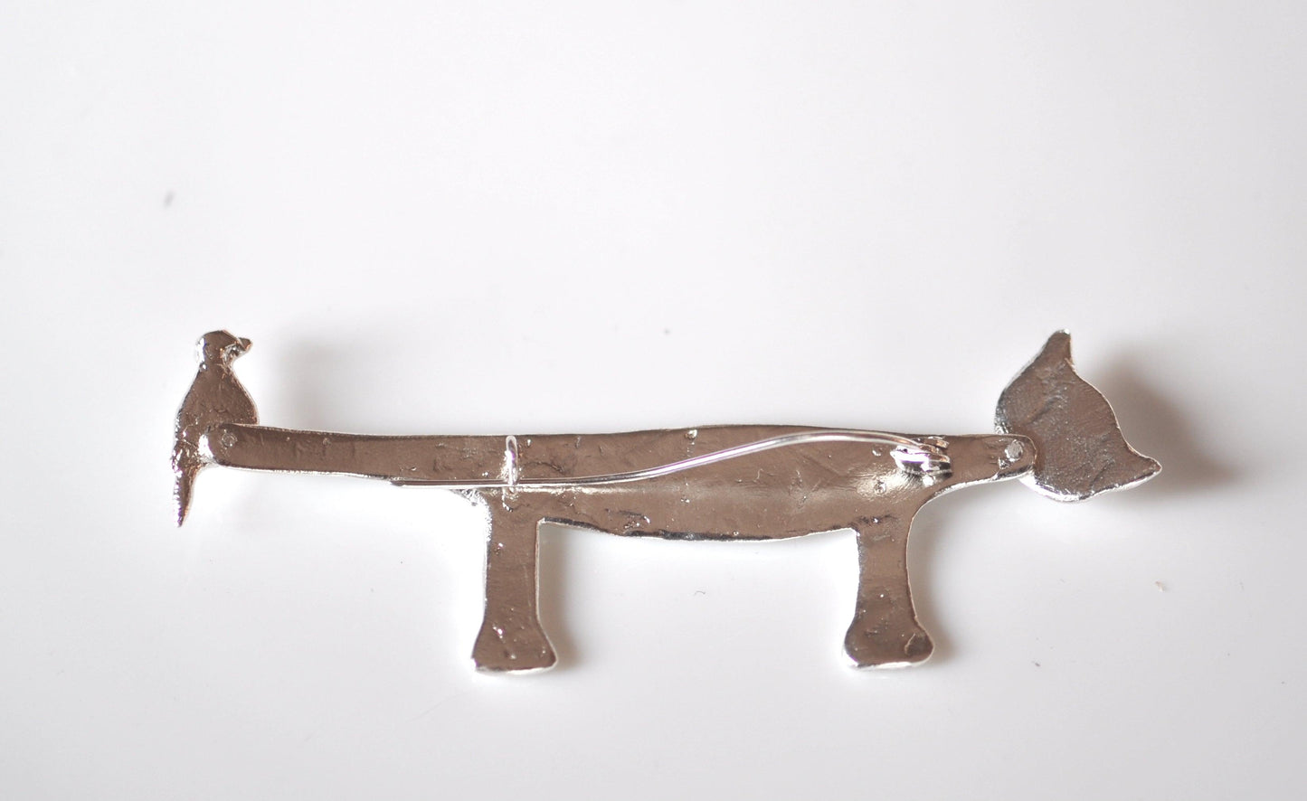 a metal dog shaped object on a white surface