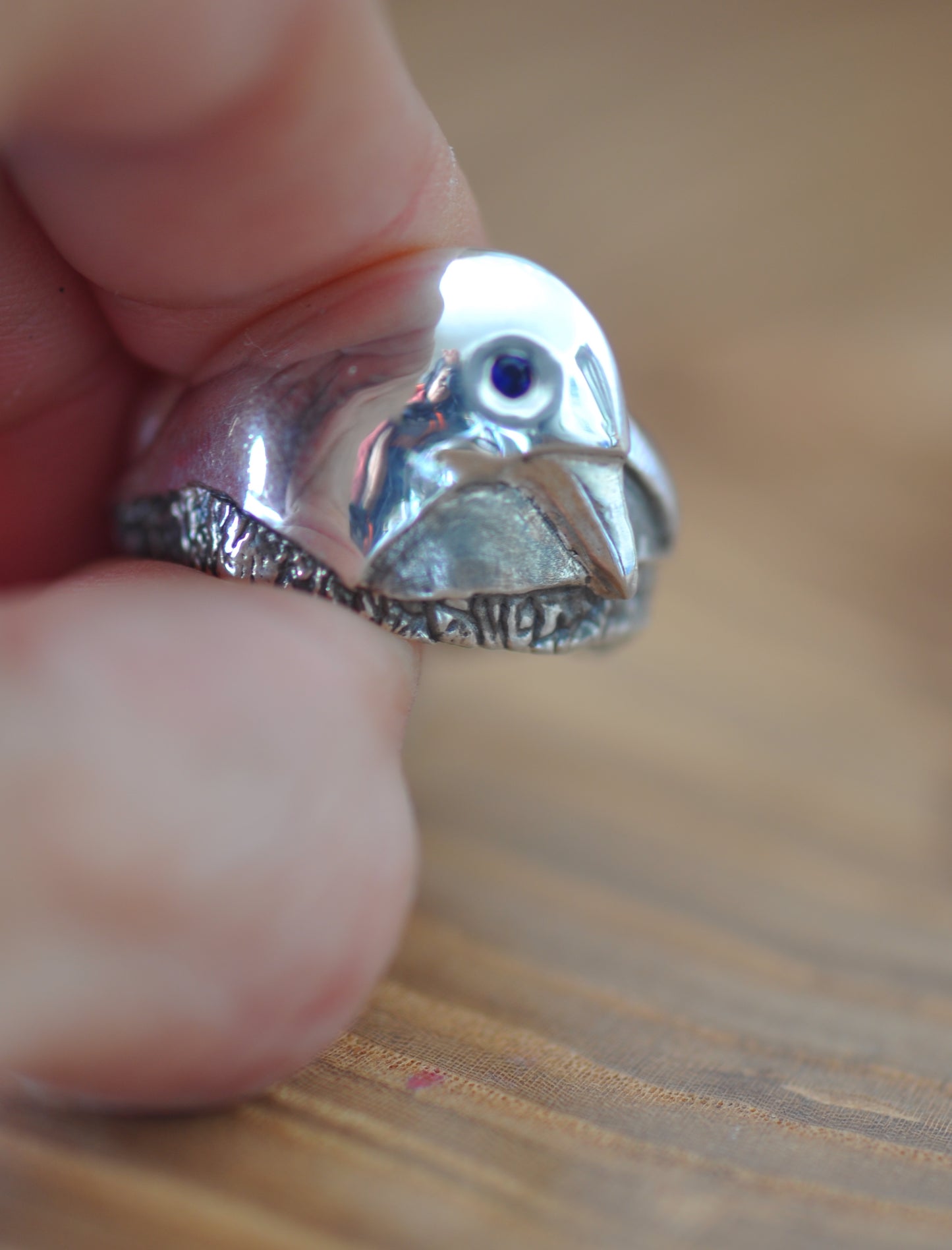 a close up of a person holding a ring with a bird on it