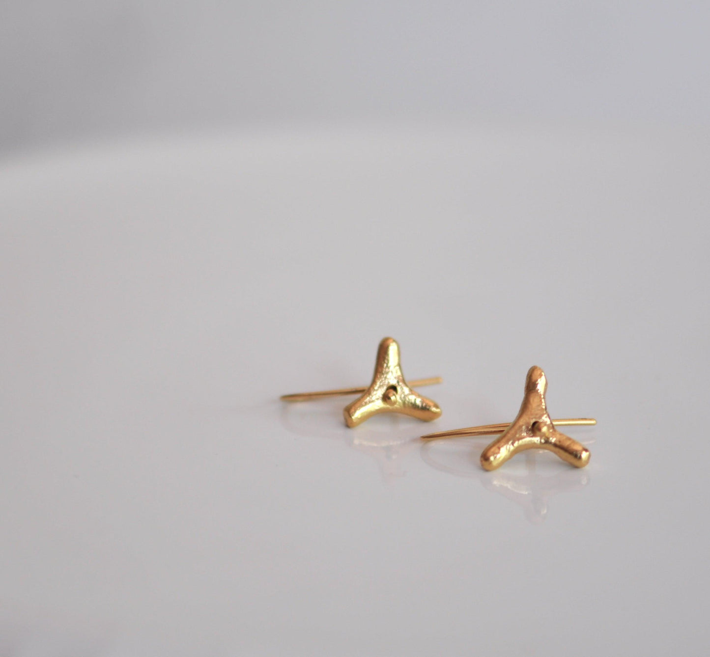 a pair of gold earrings on a white surface