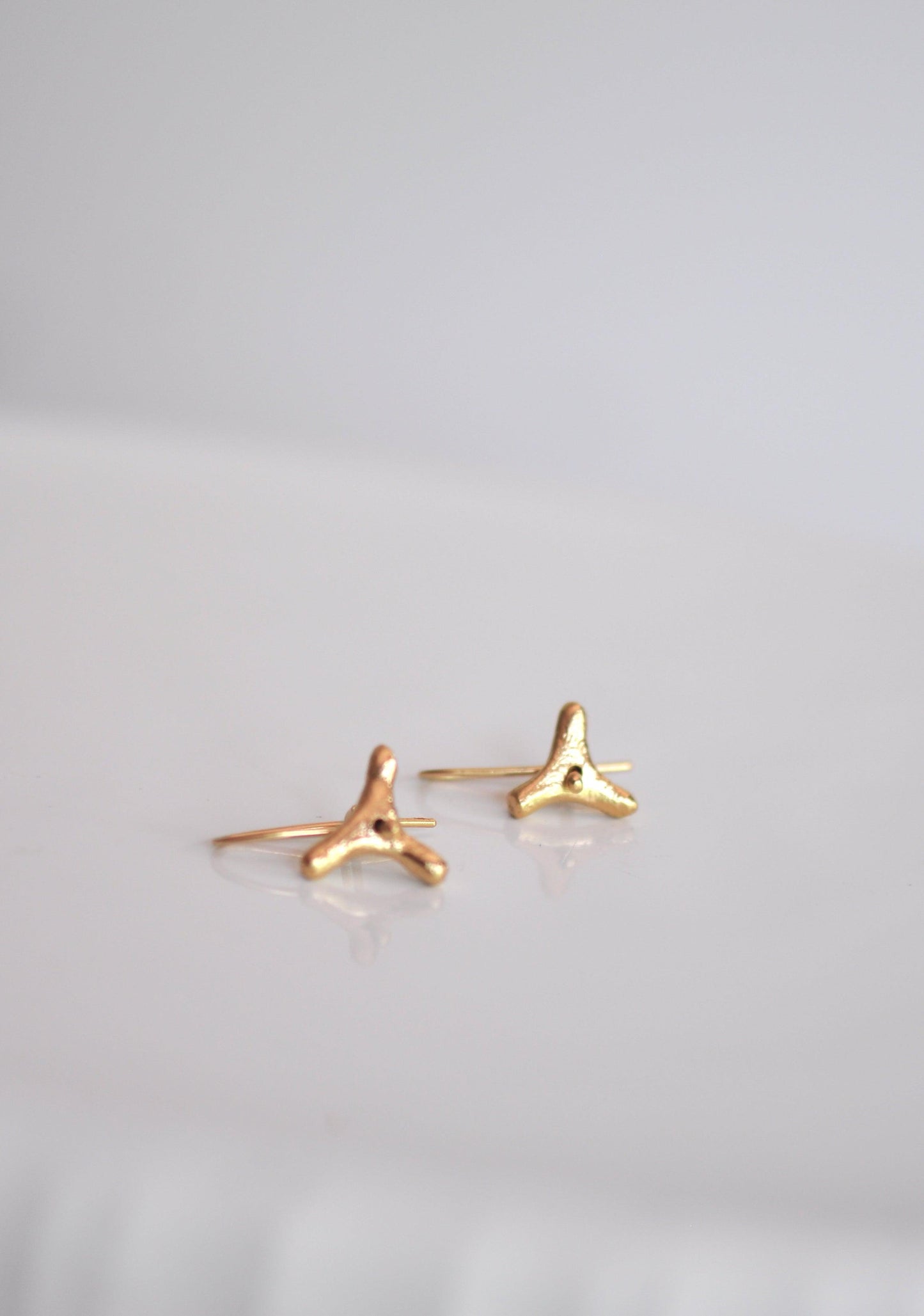 a pair of tiny gold earrings on a white surface