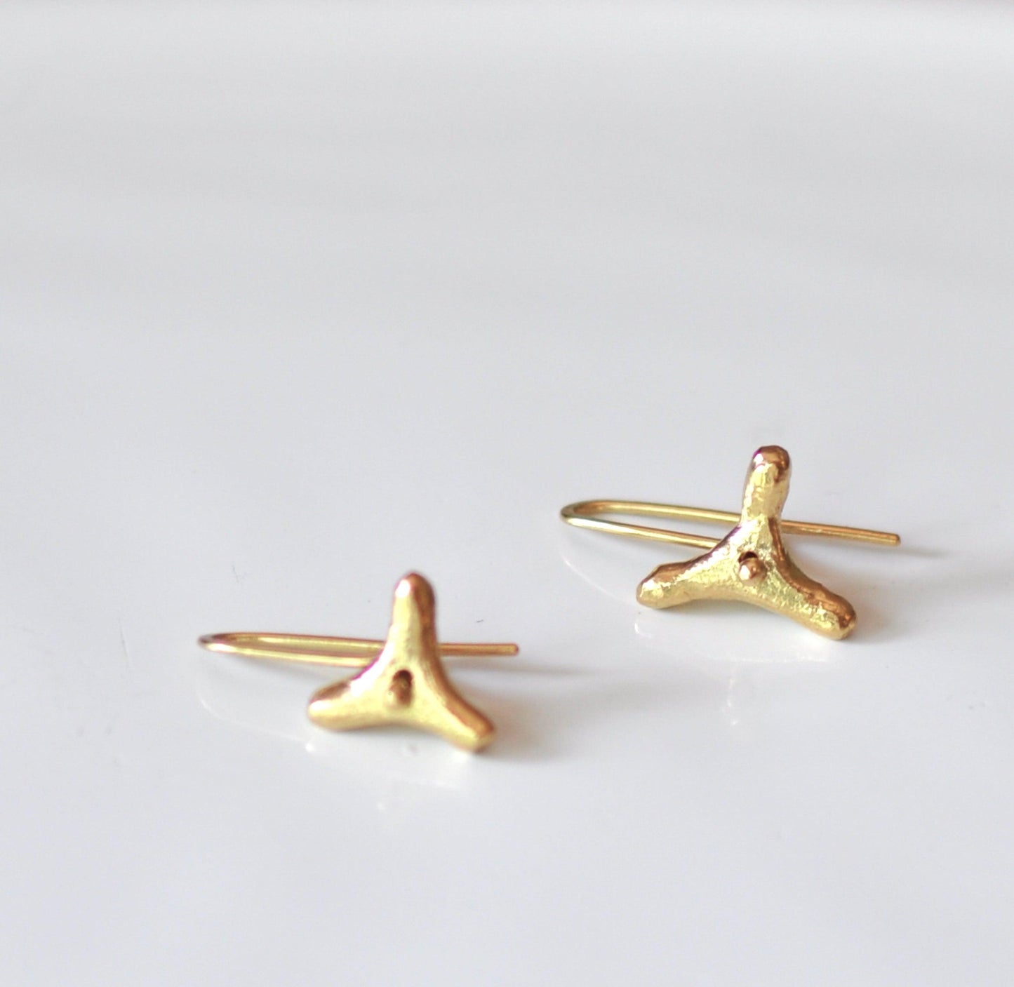 a pair of gold earrings on a white surface