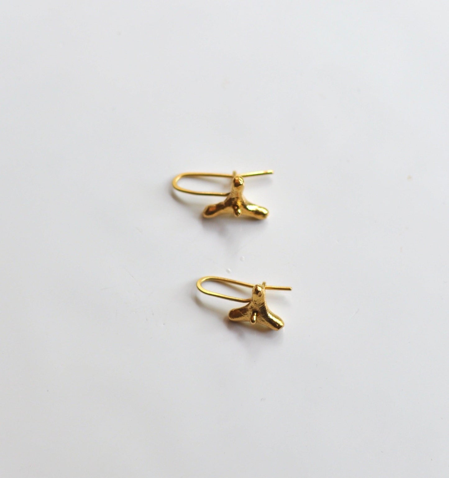 a pair of gold earrings on a white surface