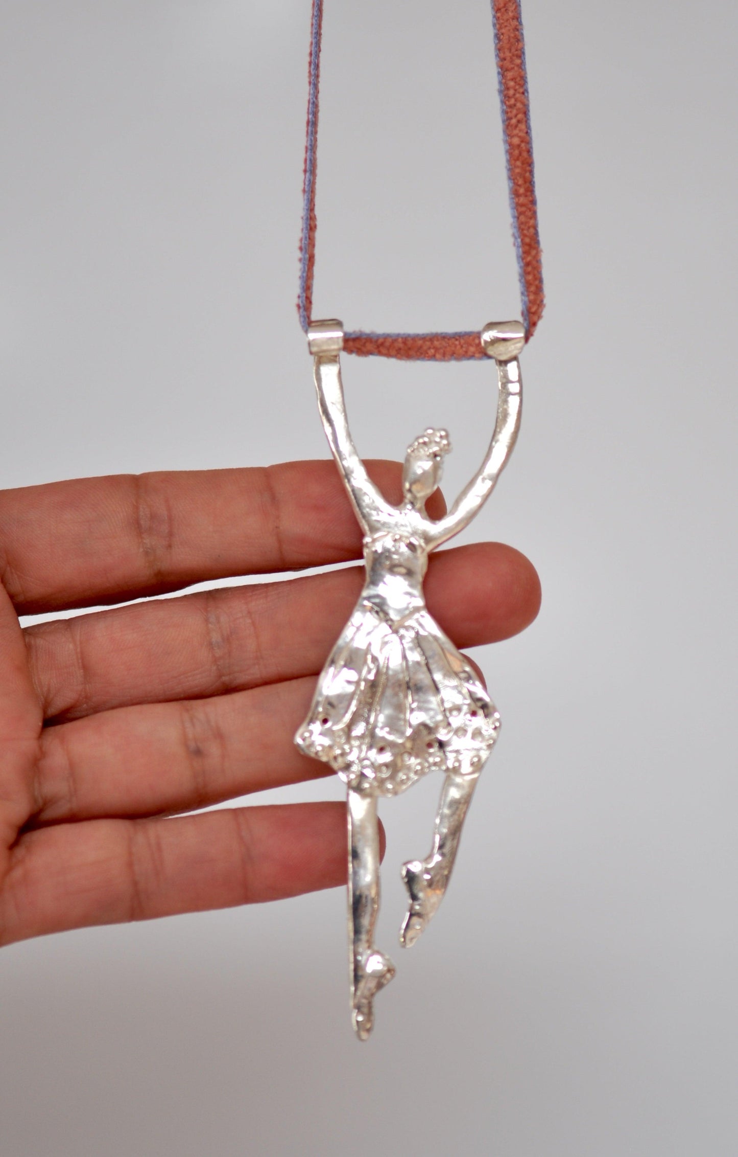 a person holding a silver pendant in their hand