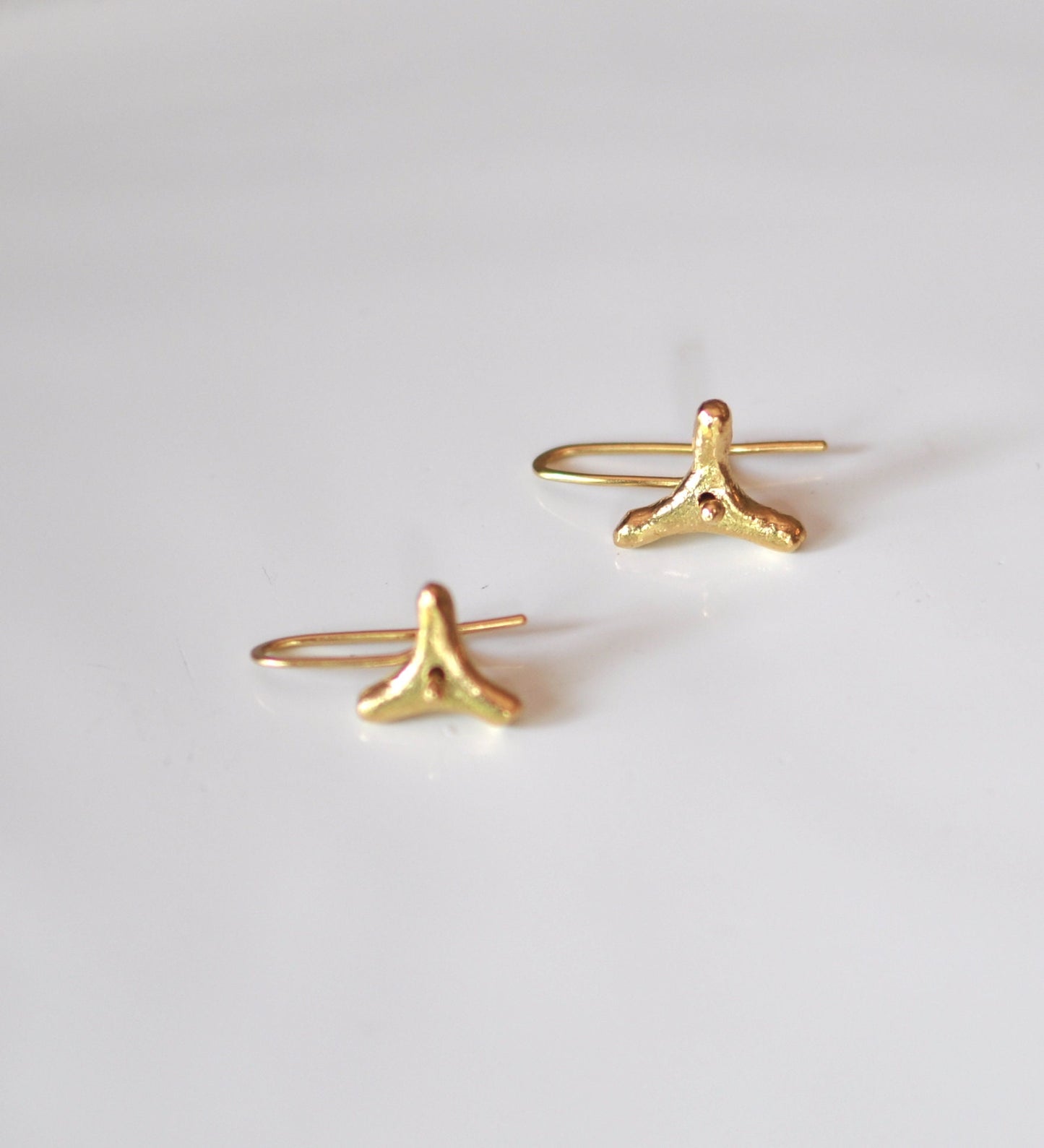 a pair of gold earrings on a white surface