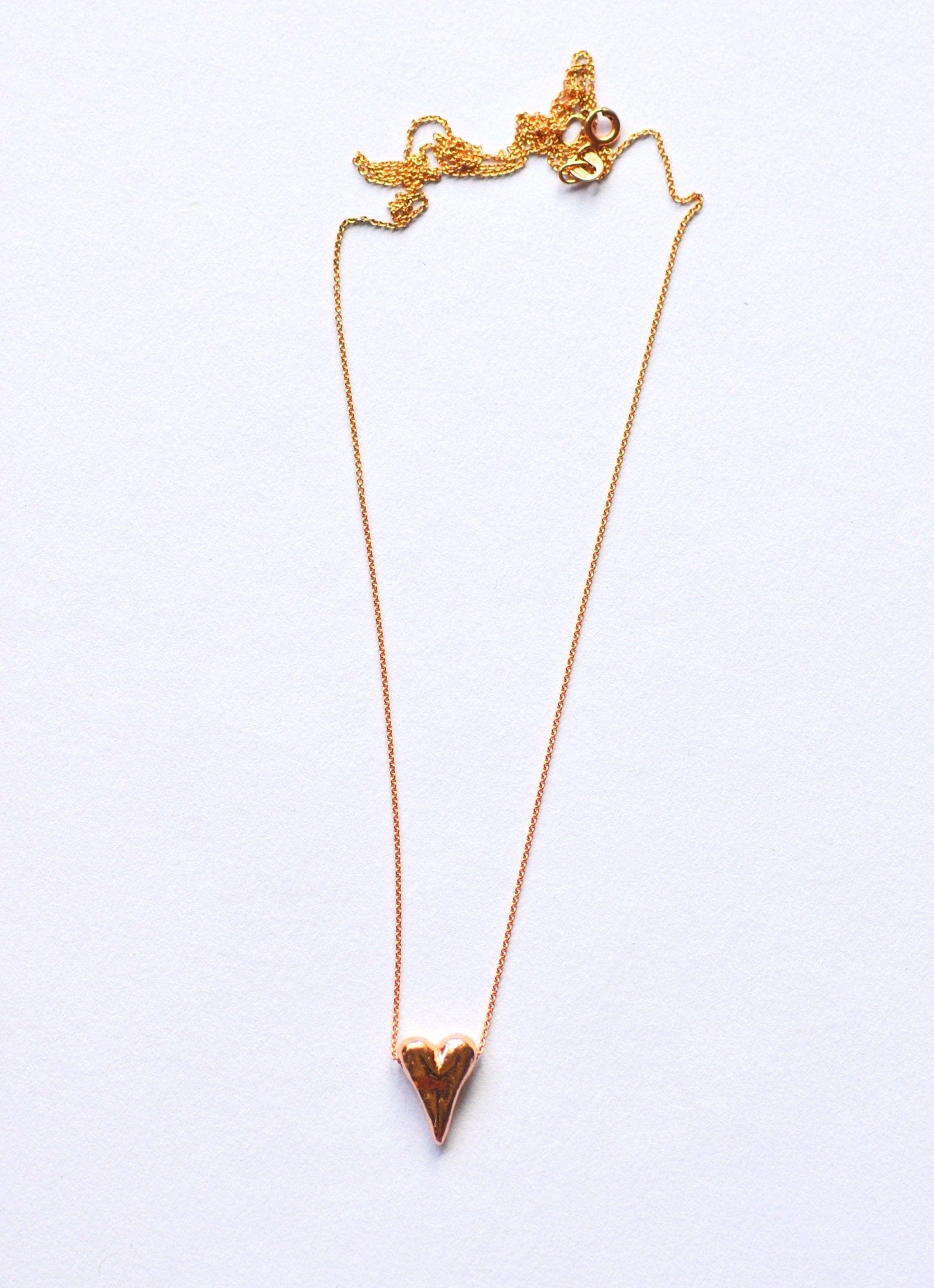 a gold necklace with a heart on it