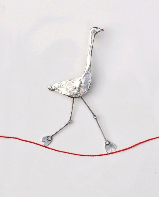 a bird made out of silver wire on a white surface