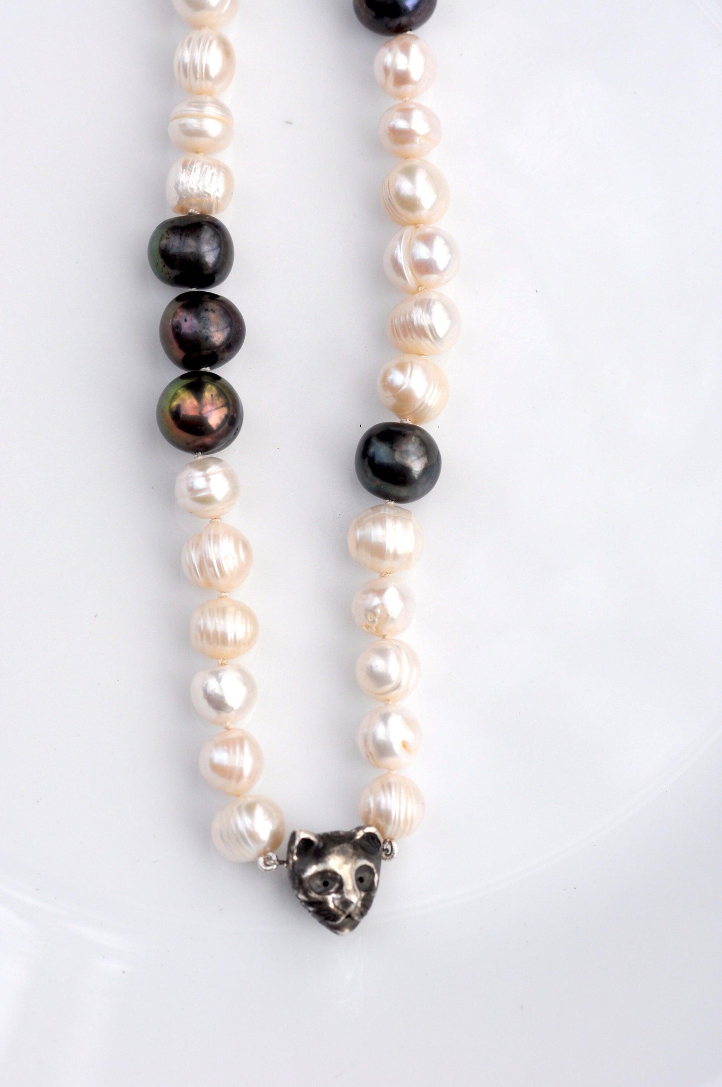 a necklace of pearls and a black and white bead