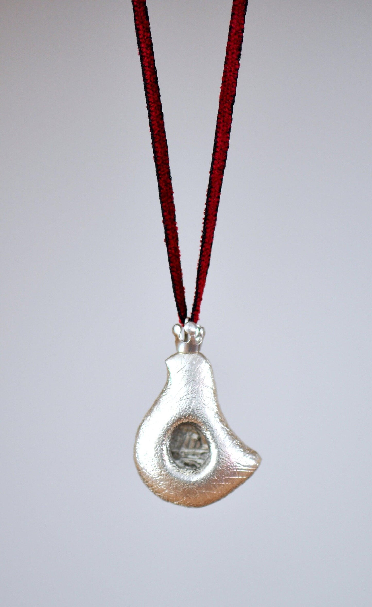 a silver pendant hanging from a red cord