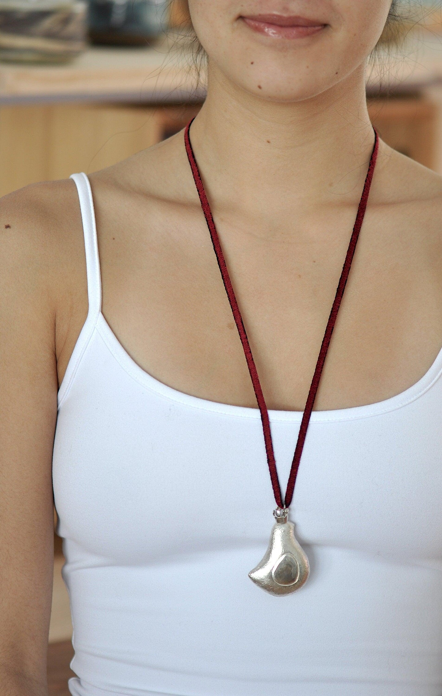 a woman wearing a white tank top and a red necklace