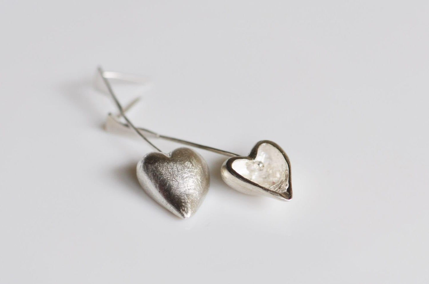 a pair of silver heart earrings on a white background