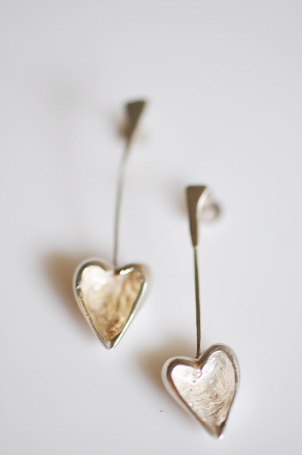 a pair of silver heart earrings on a white background