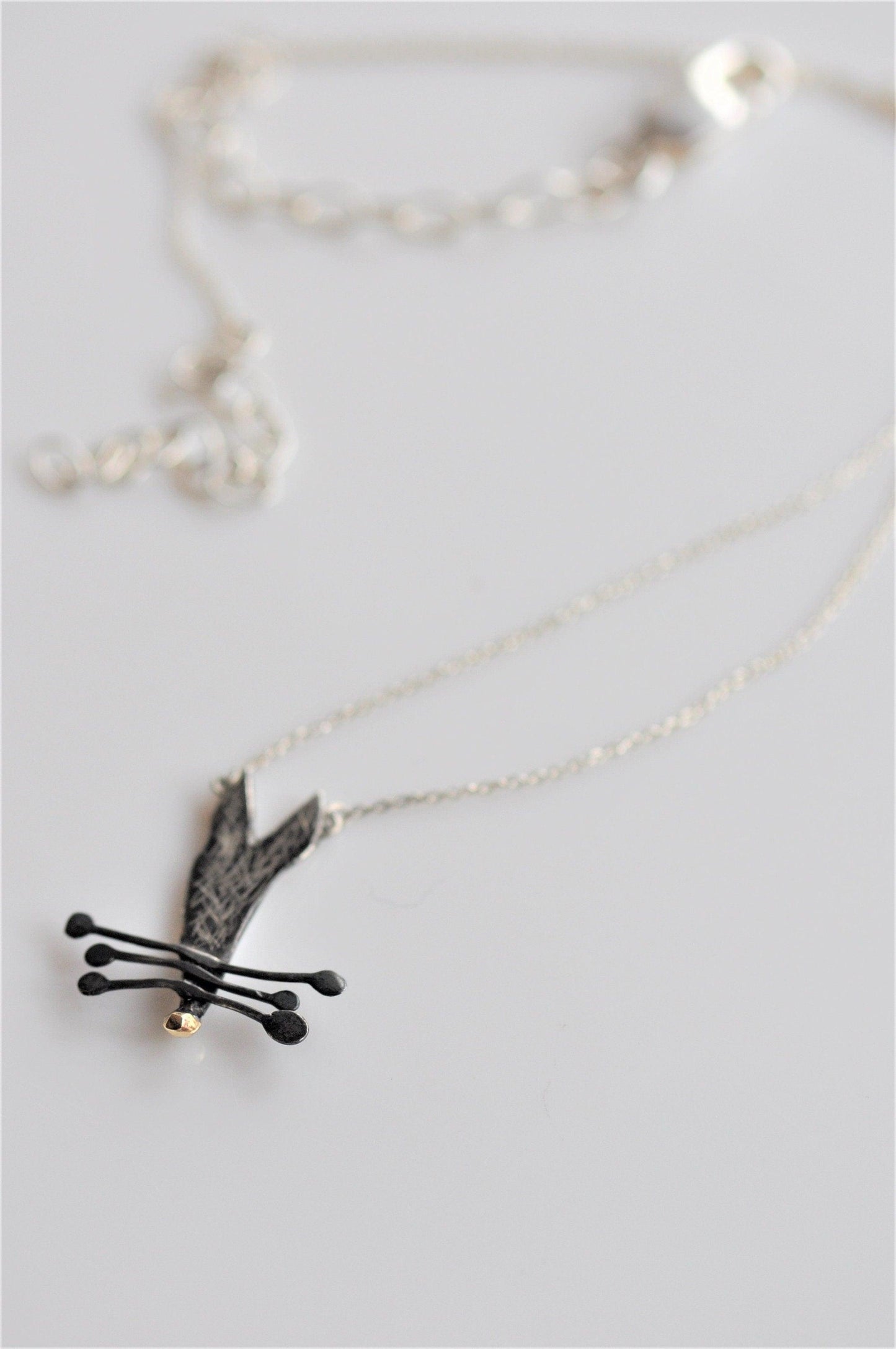 a silver necklace with a black bird on it