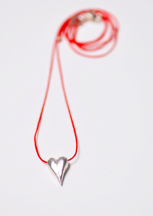 a red string with a silver heart on it