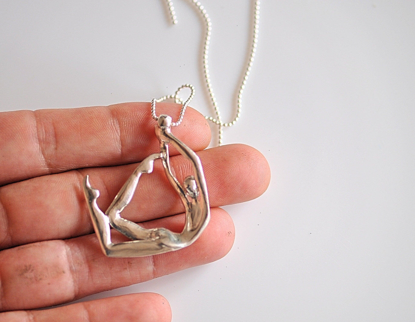 a person is holding a silver pendant in their hand