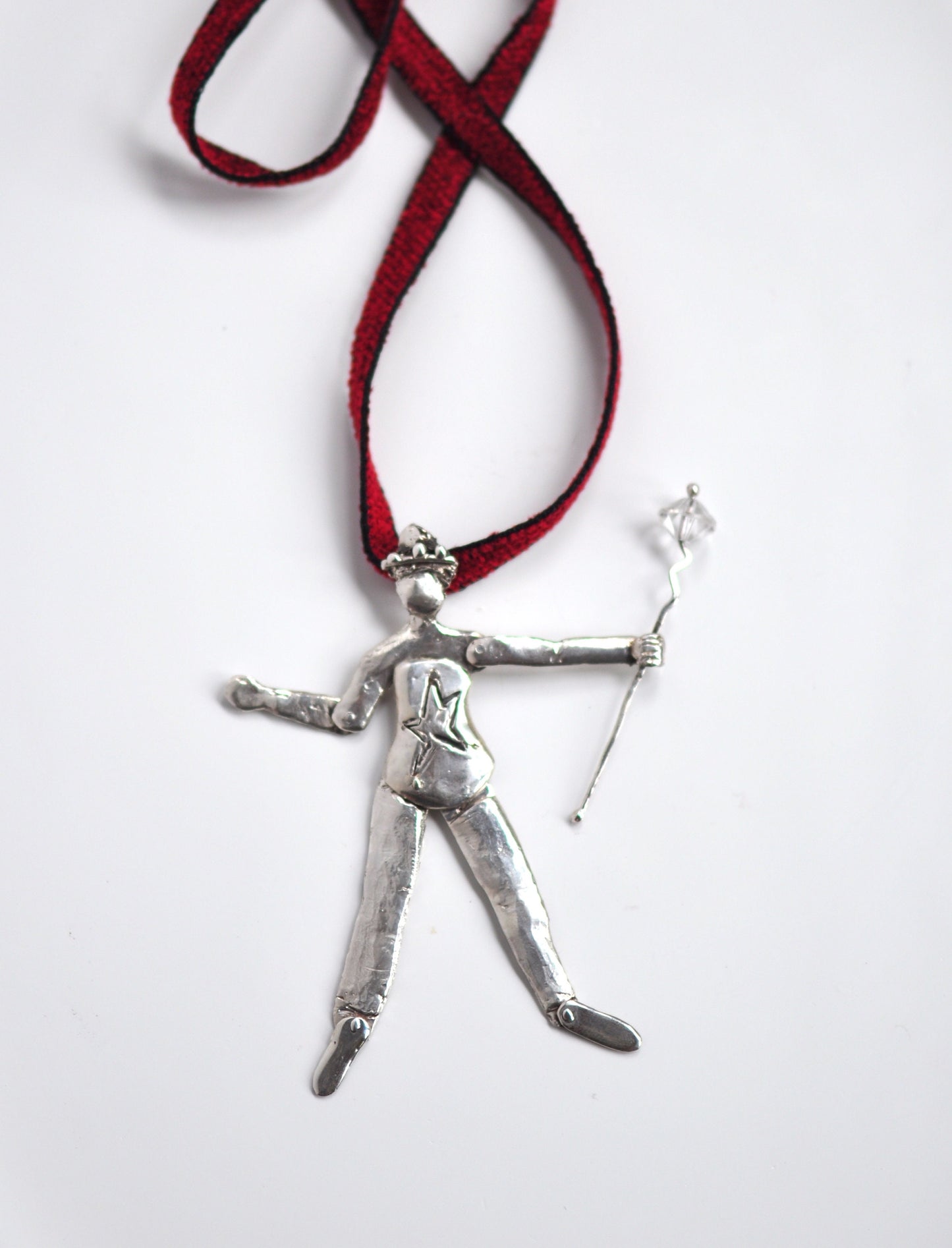 a silver pendant with a red ribbon on a white background