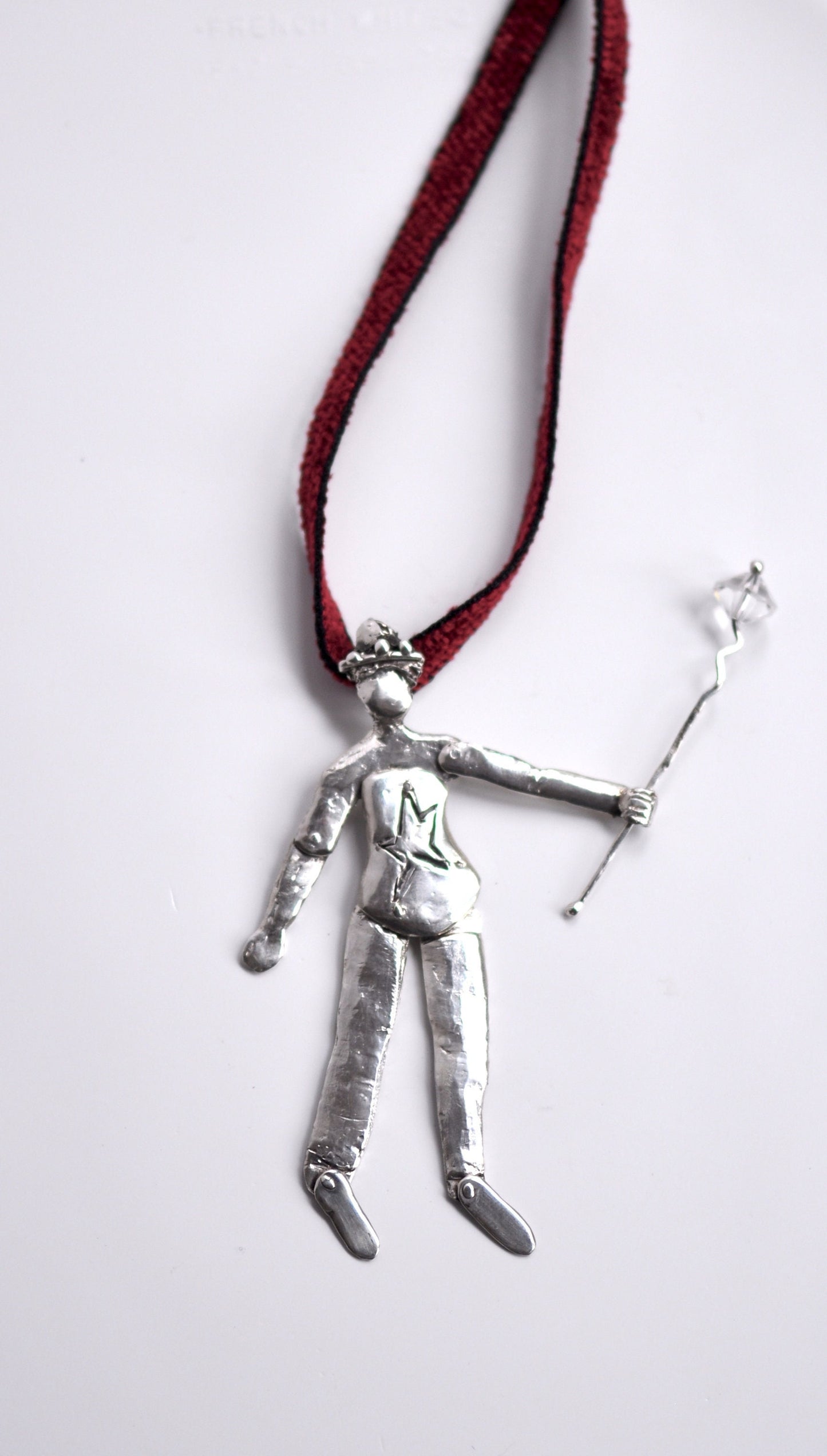 a silver pendant with a man holding a stick