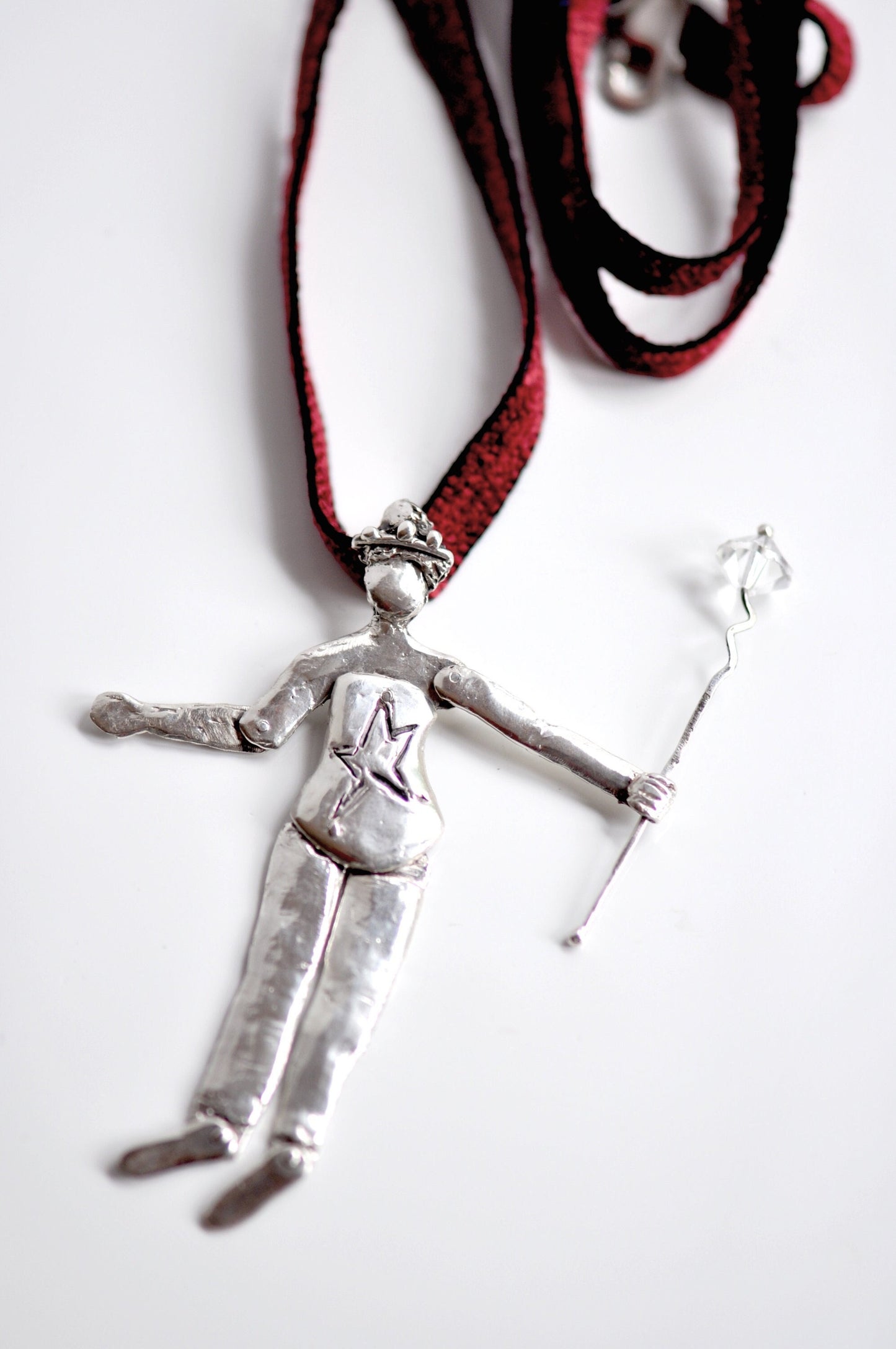 a necklace with a silver figure on a red cord