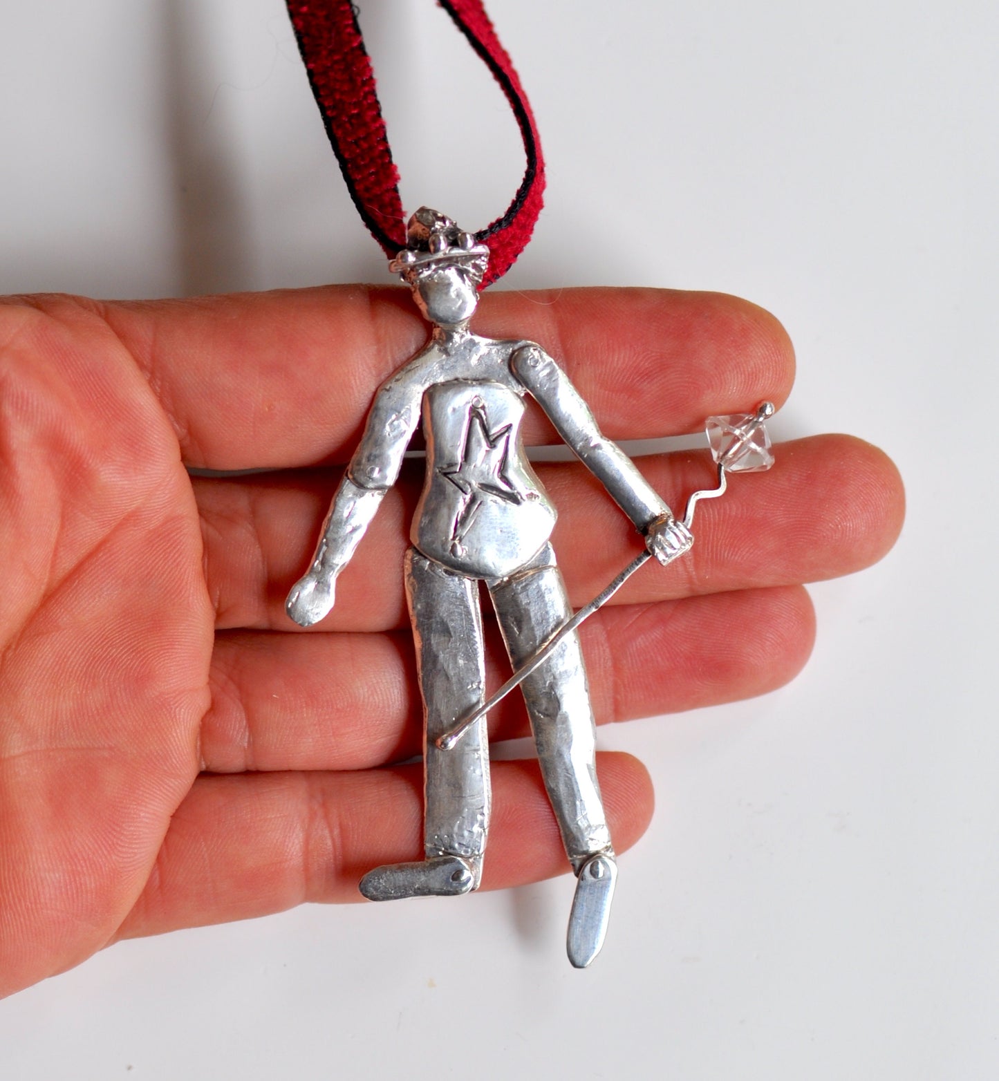 a person is holding a silver pendant in their hand