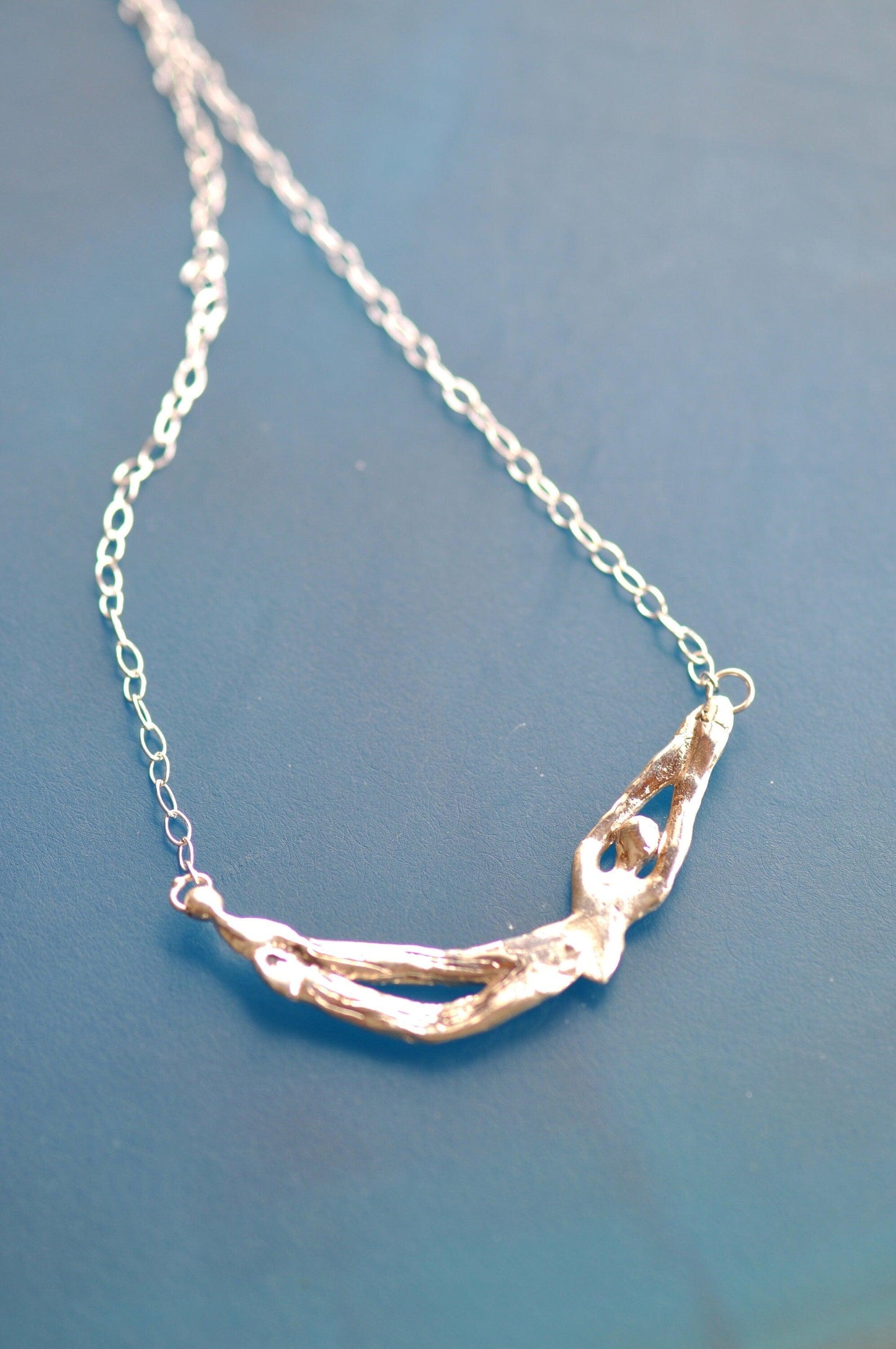 a close up of a silver necklace on a blue surface