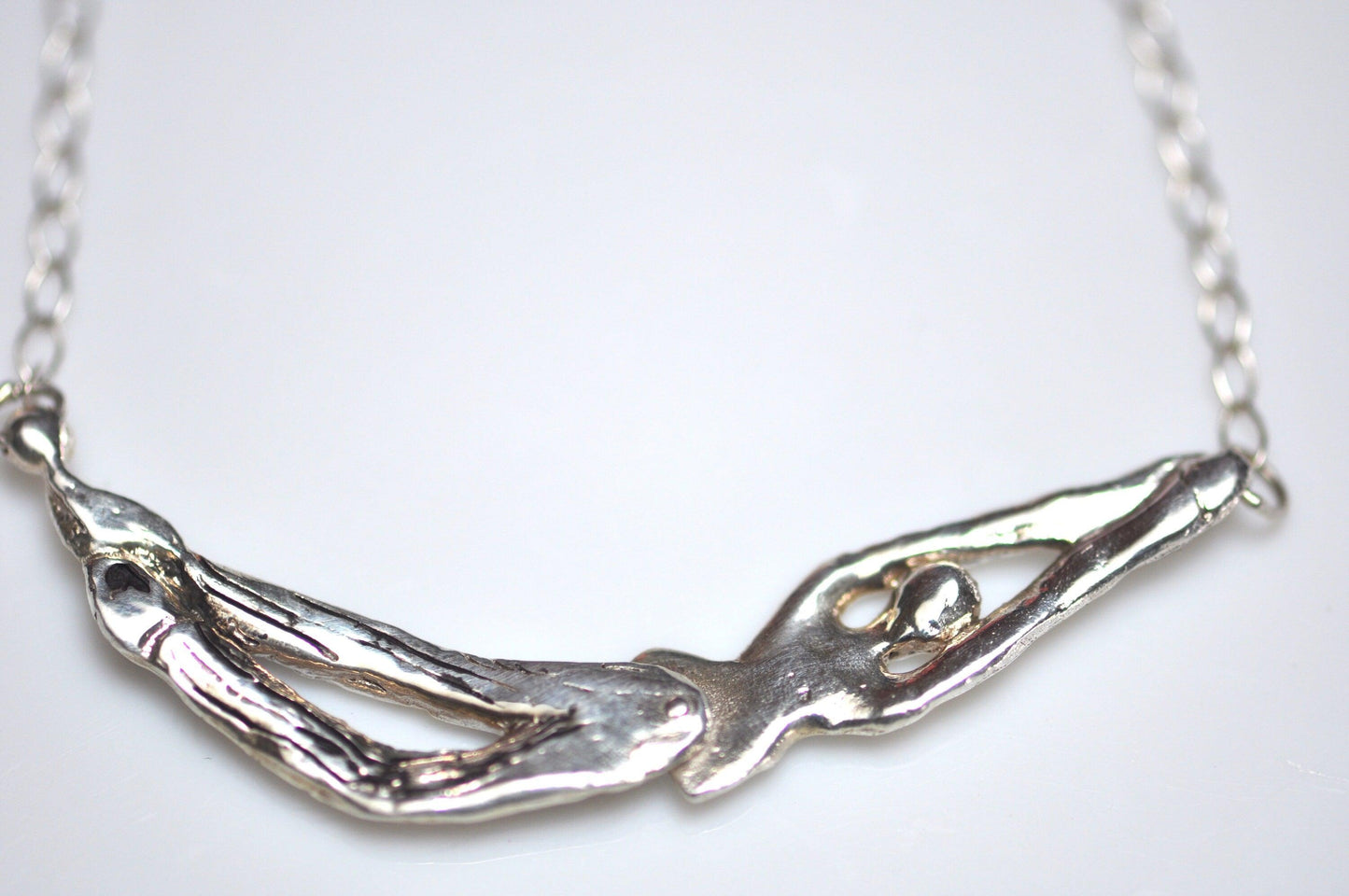 a close up of a silver necklace on a white surface