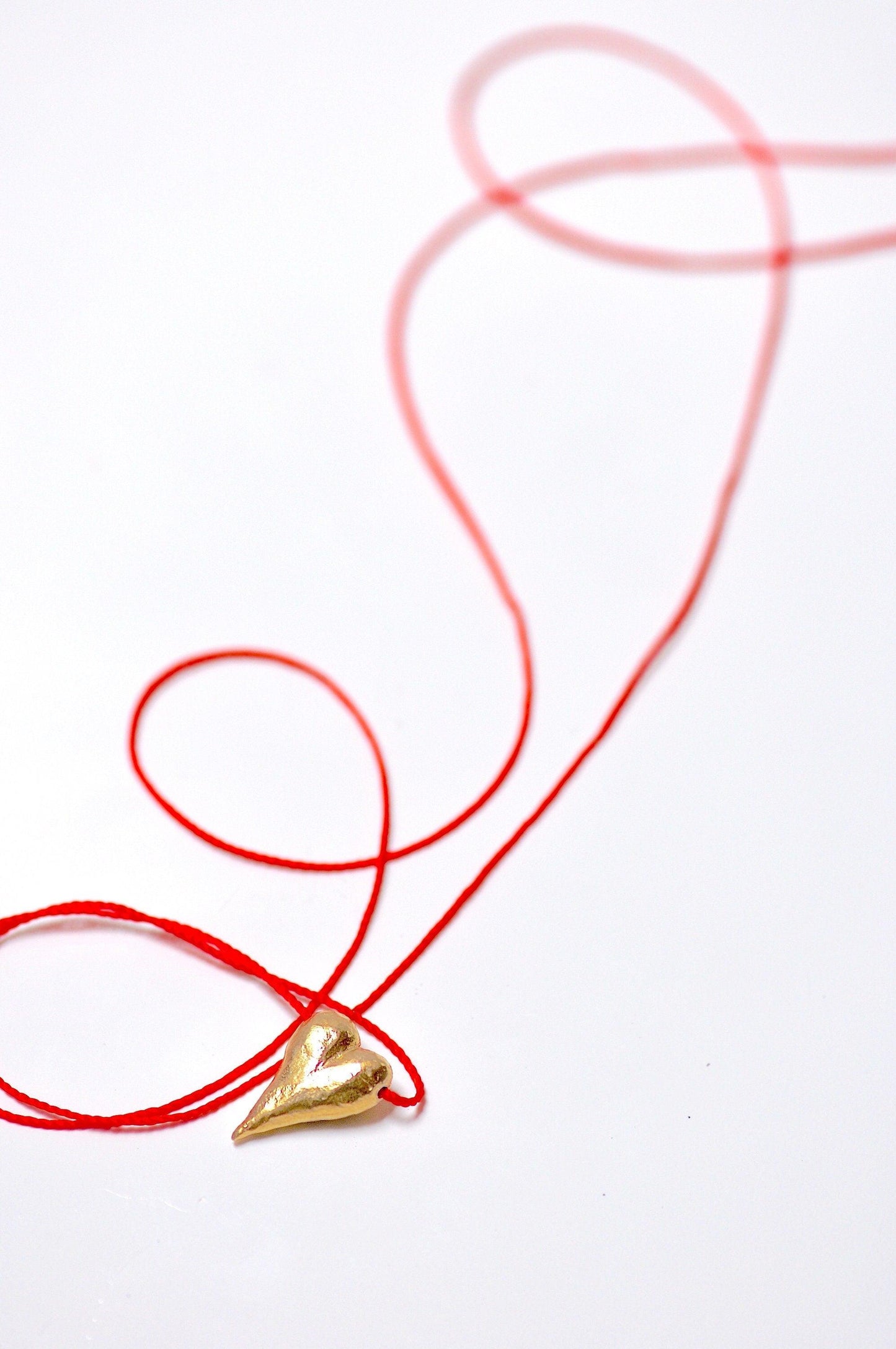 a piece of red string with a gold object on it