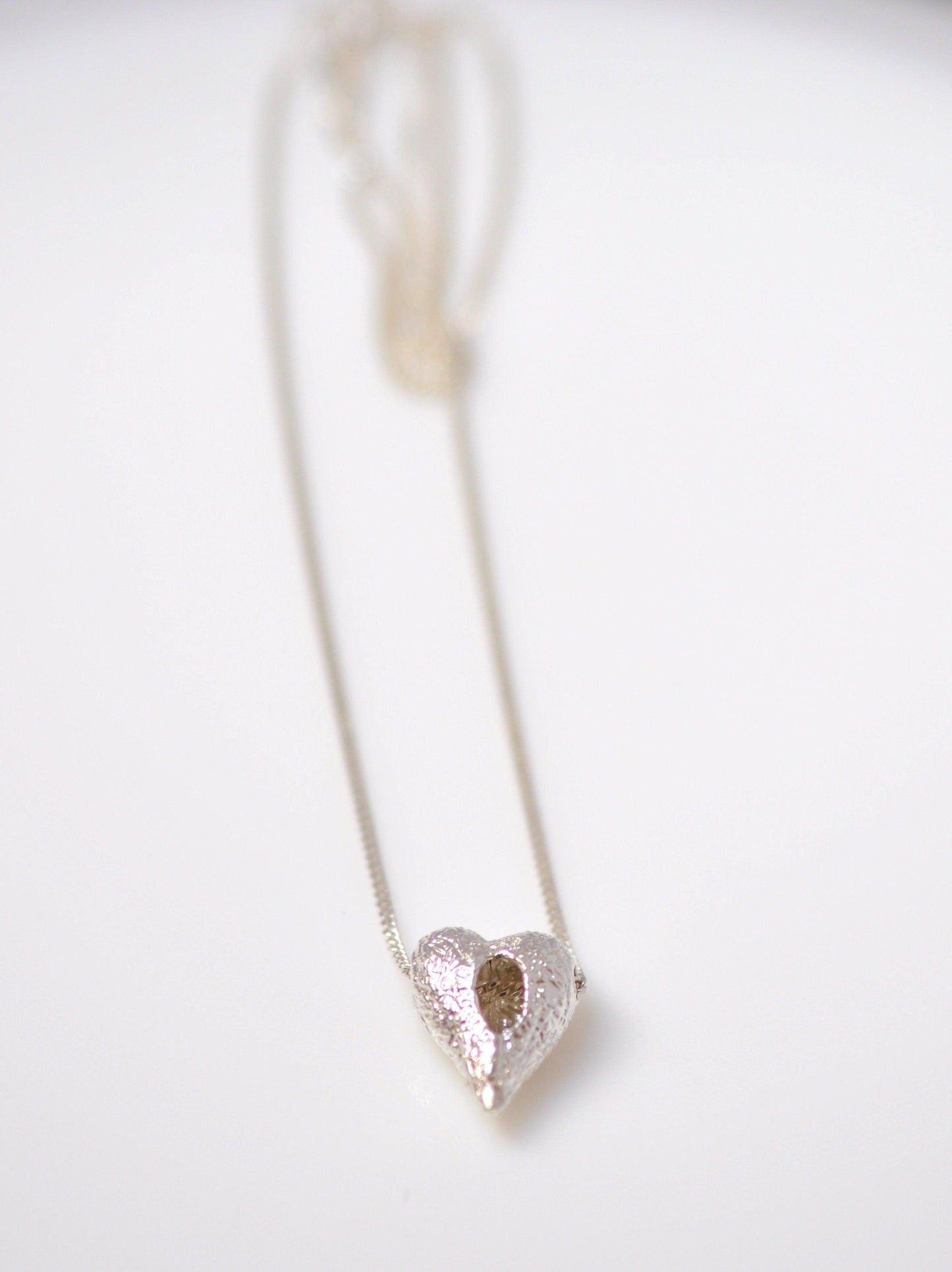 a heart shaped pendant on a white surface