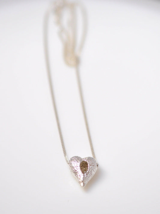 a heart shaped pendant on a white surface