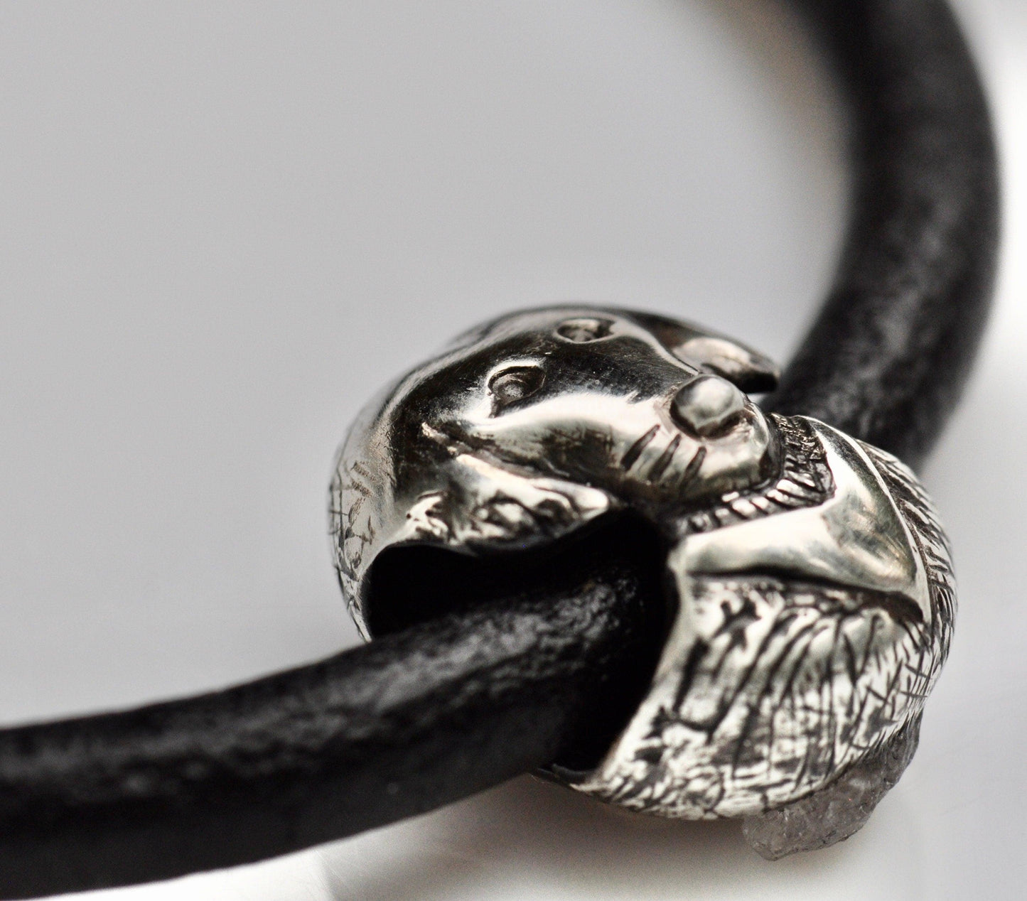 a black leather bracelet with a silver skull charm