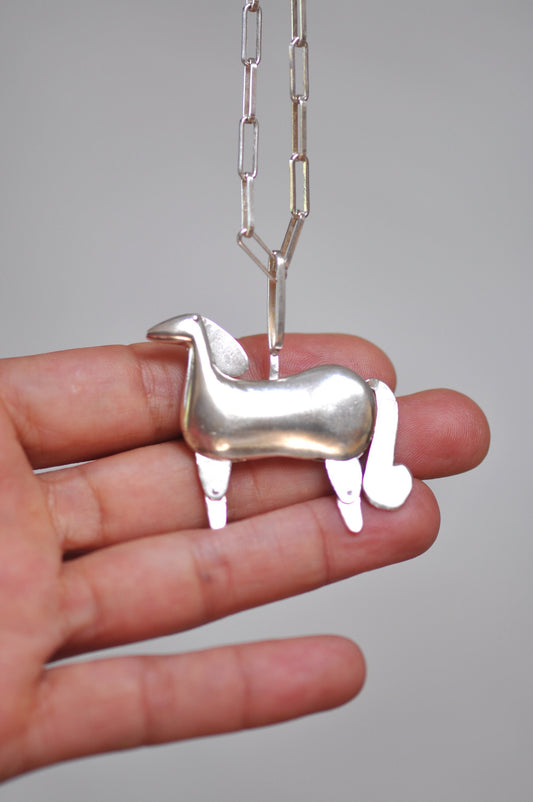 a person holding a tiny toy horse on a chain