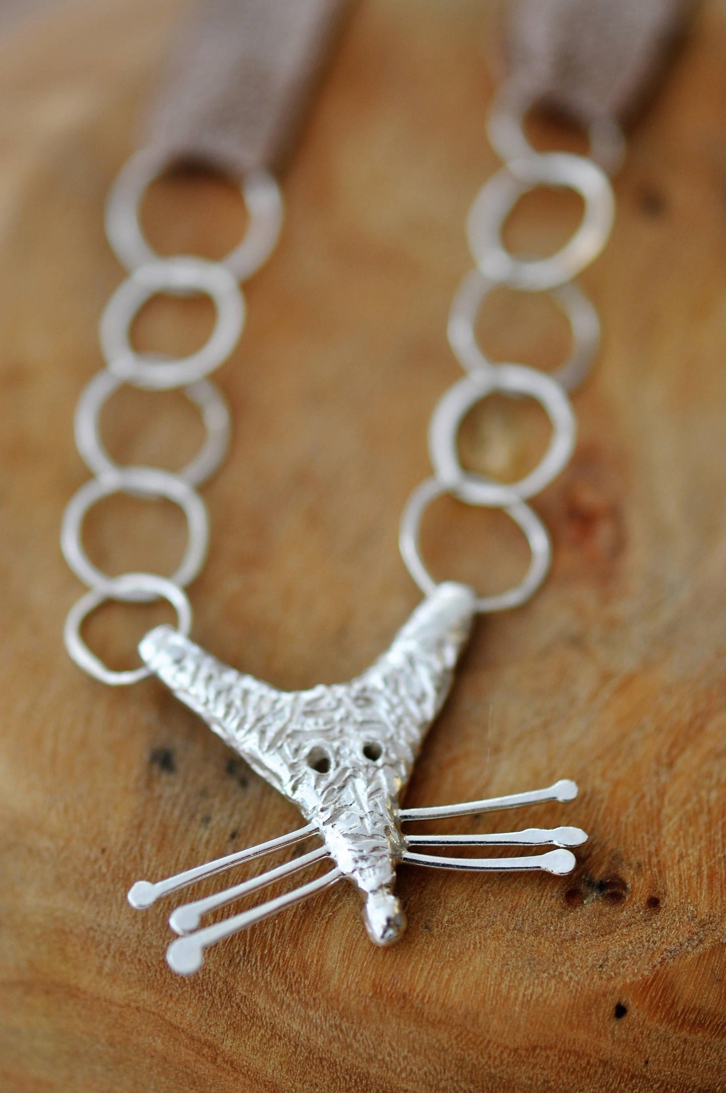 a silver necklace with a cat design on it