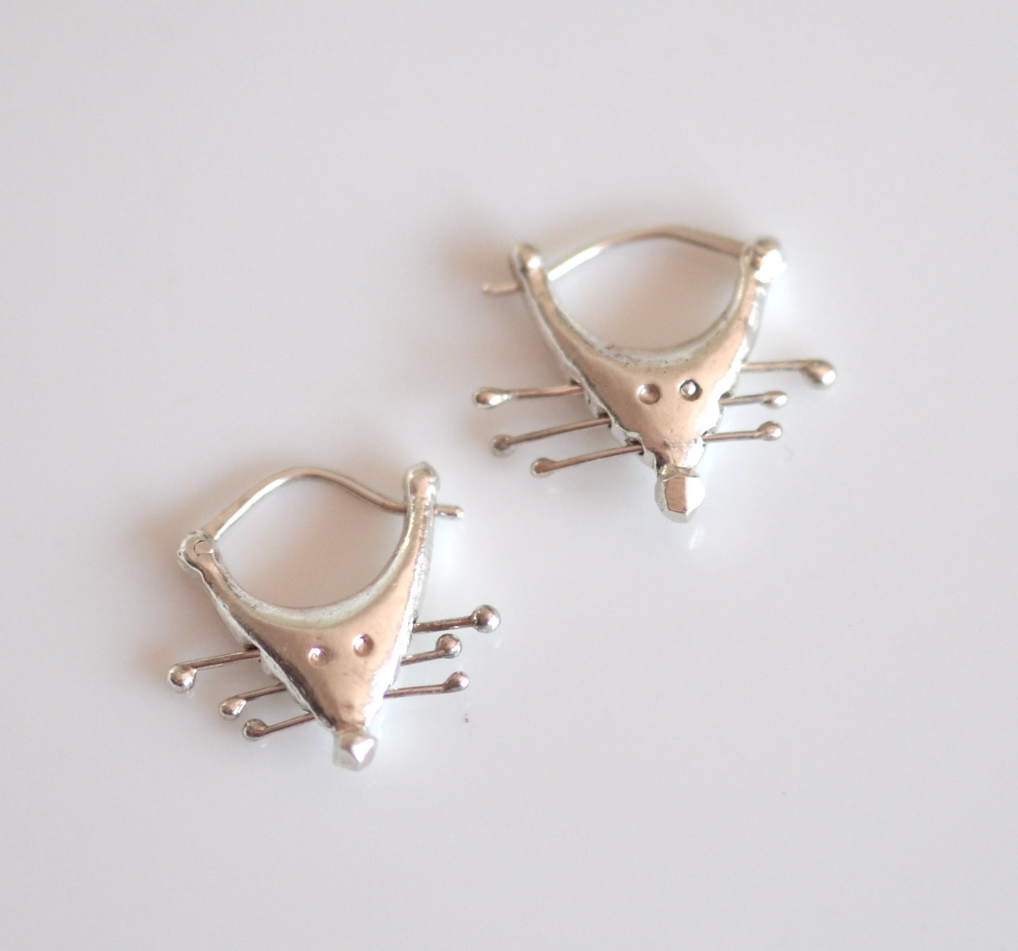 a pair of silver earrings sitting on top of a table