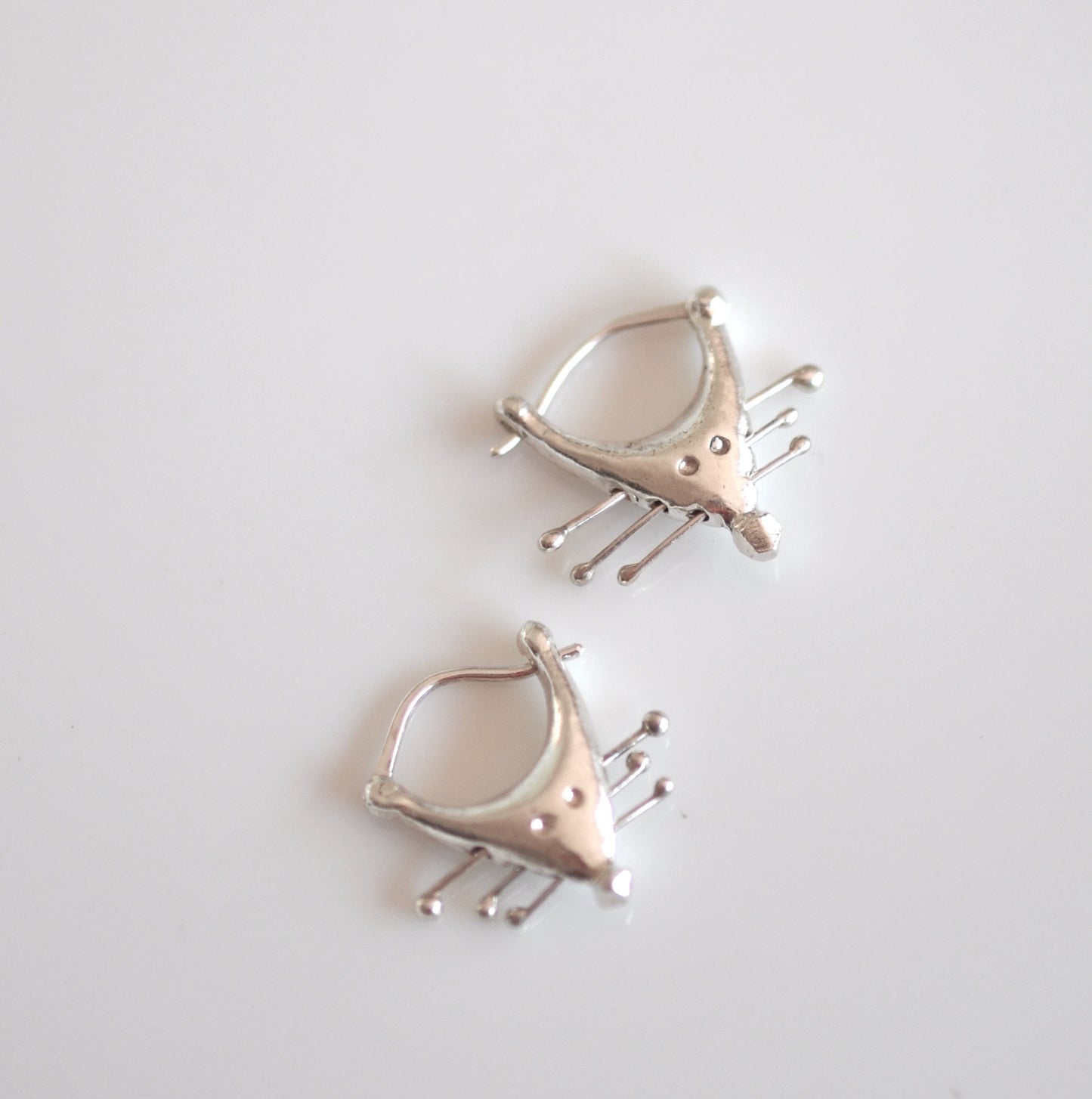 a pair of silver earrings sitting on top of a table