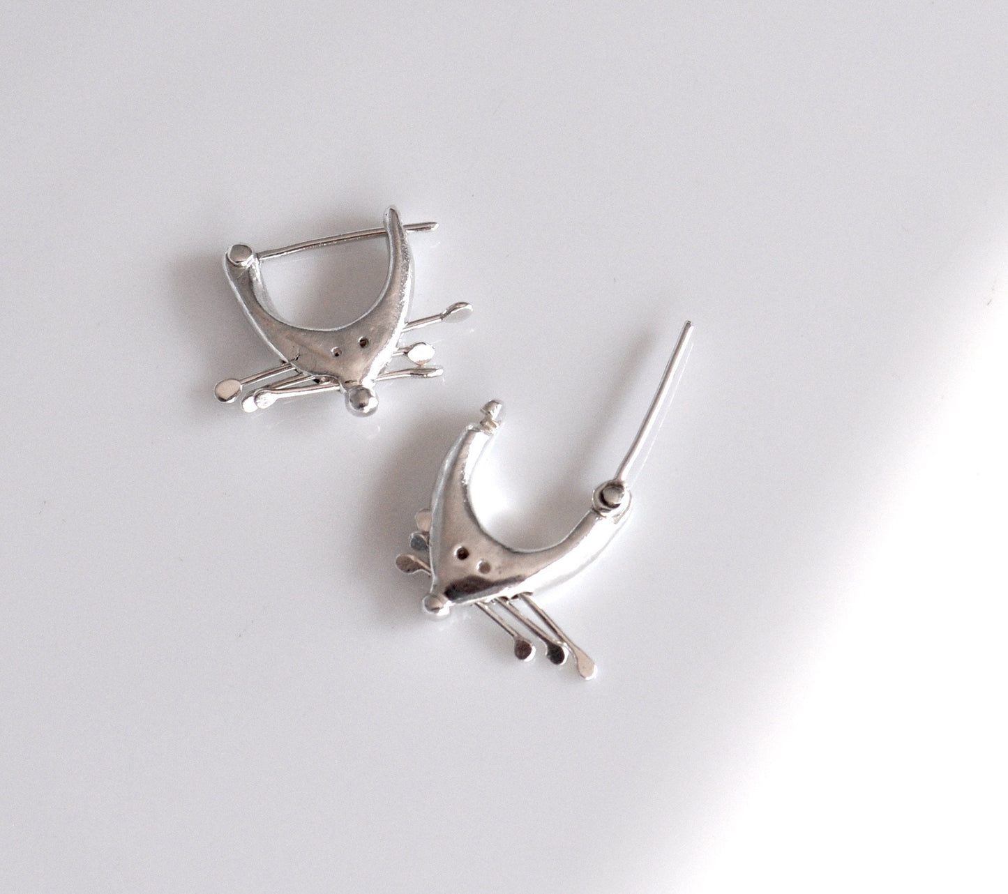 a pair of silver earrings on a white surface