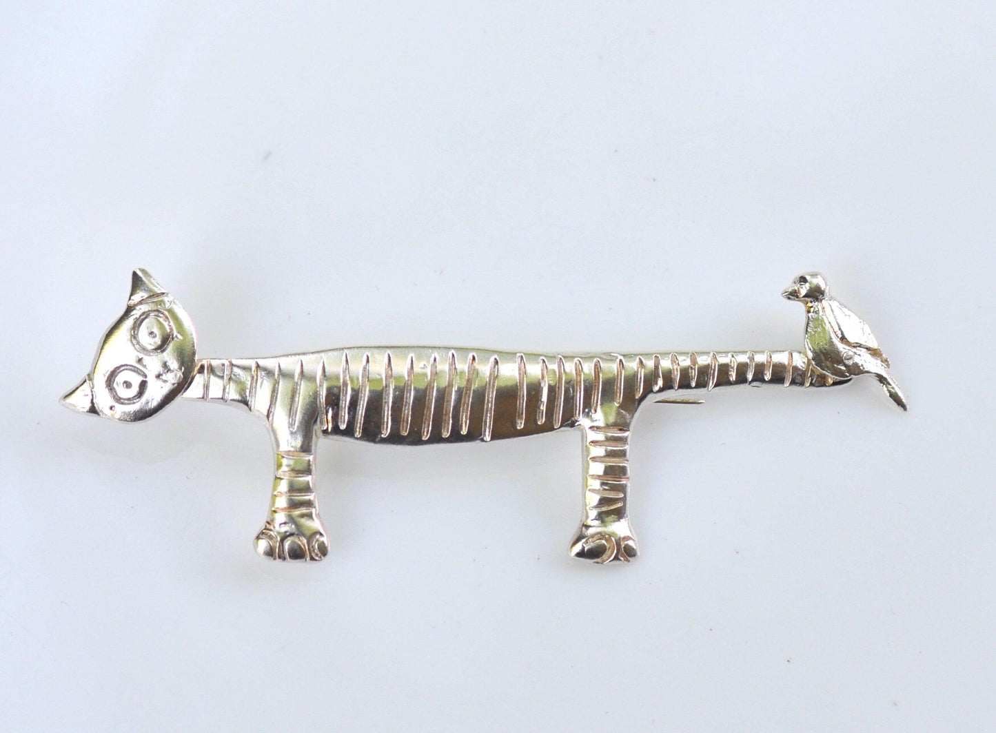 a silver brooch depicting a zebra and a bird