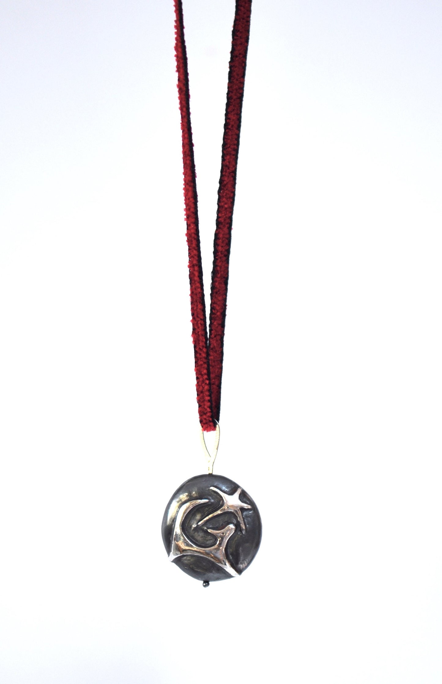 a necklace with a black and silver medallion hanging from it's side