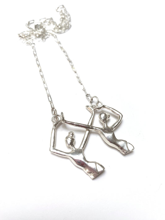 a silver necklace with two people on it