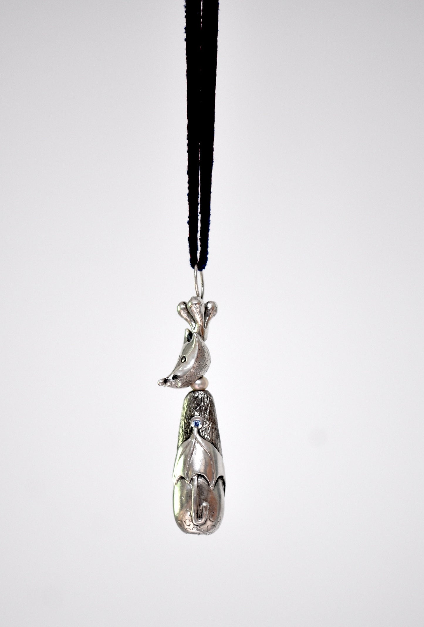 a silver figurine hanging from a black cord