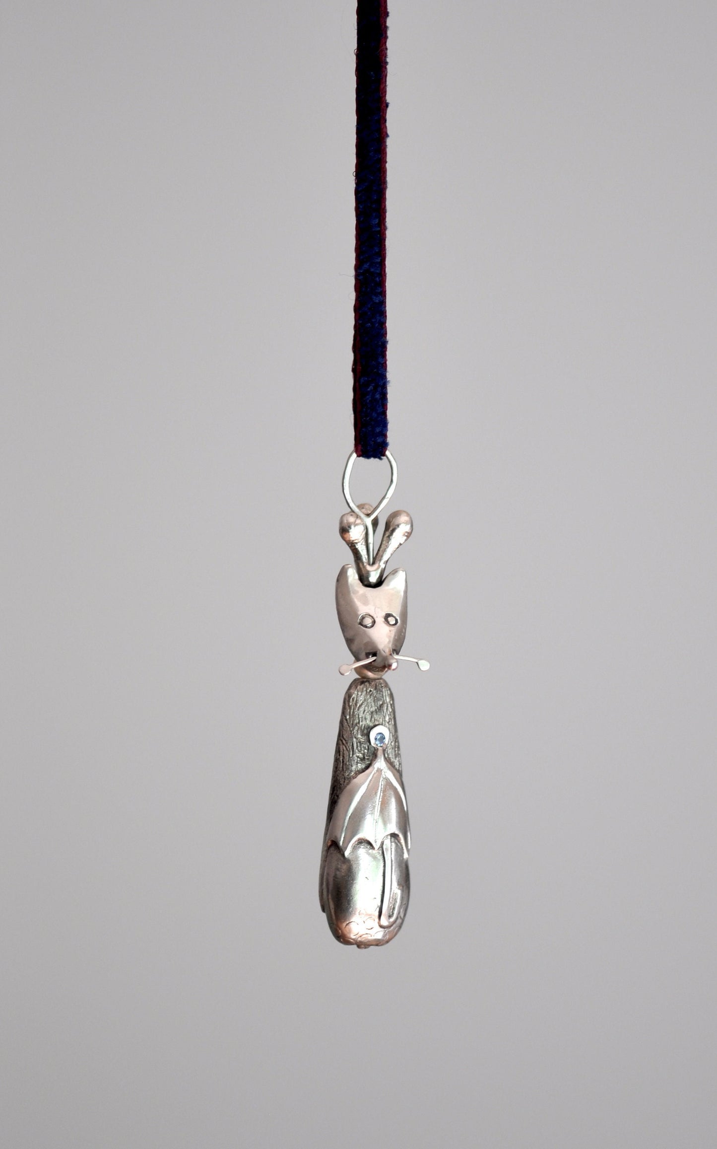 a silver cat ornament hanging from a cord