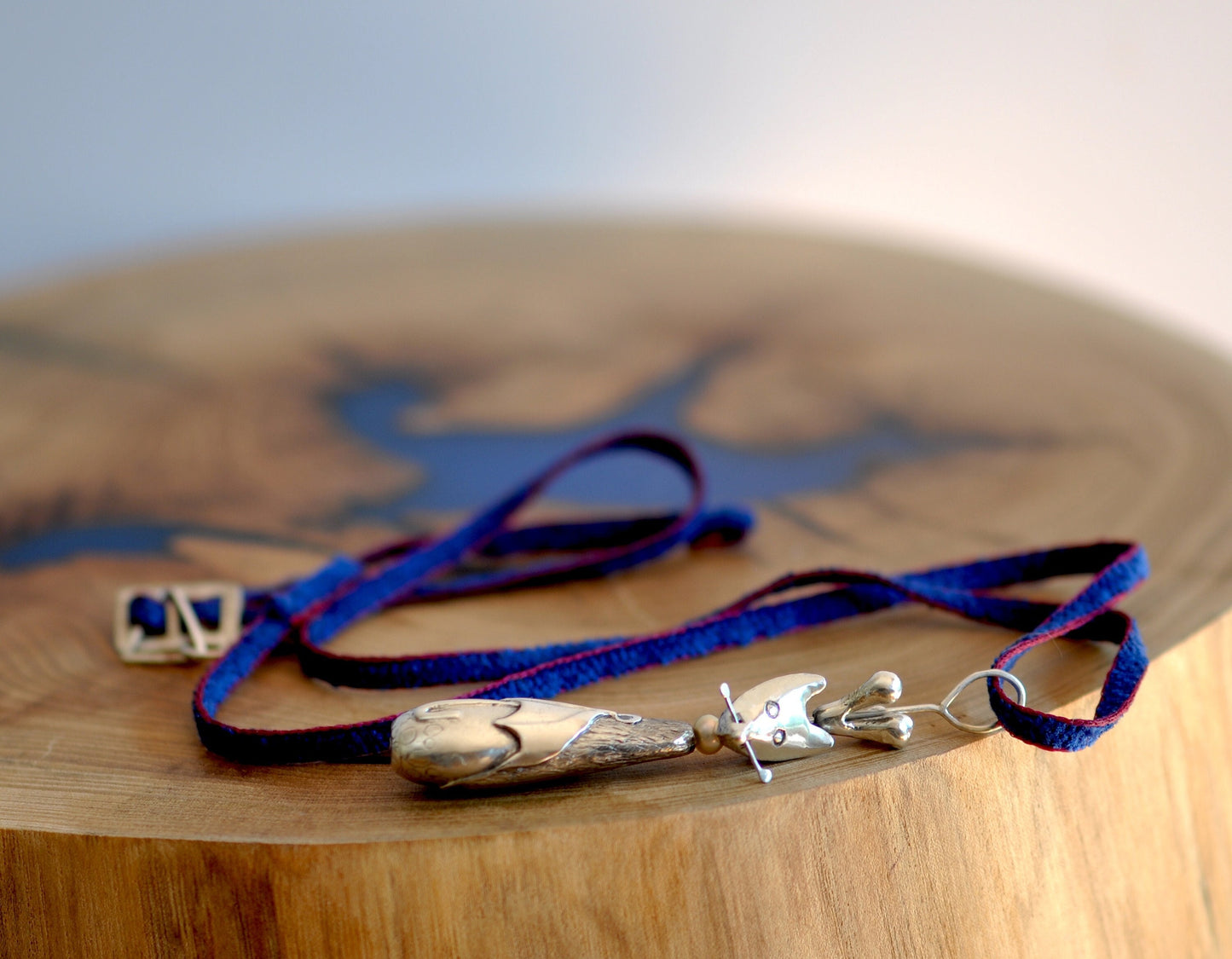 a wooden table topped with a blue and silver necklace