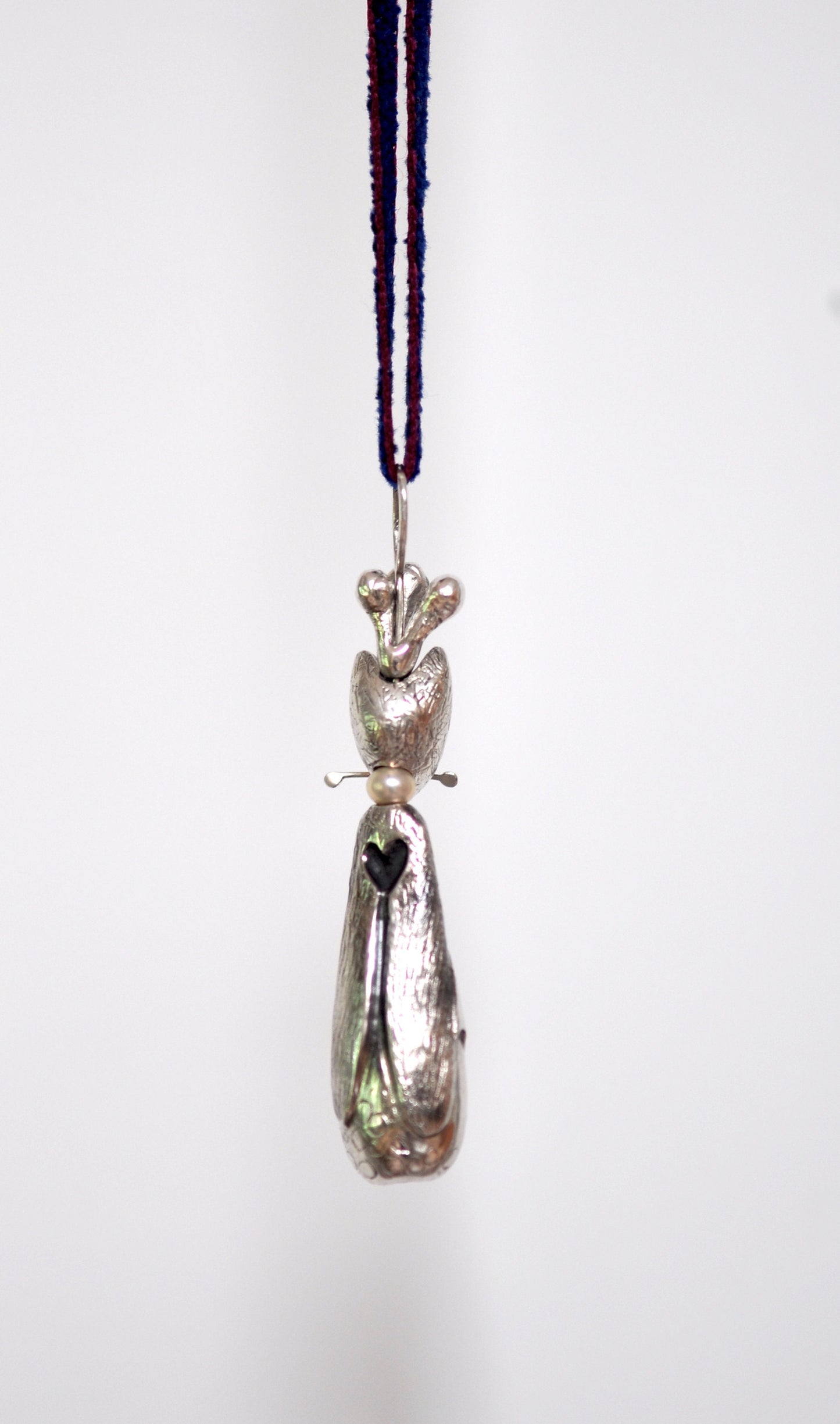 a silver object hanging from a cord on a white wall