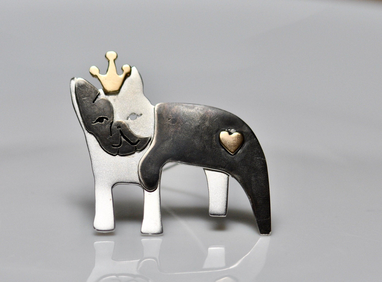 a silver and gold brooch with a dog wearing a crown