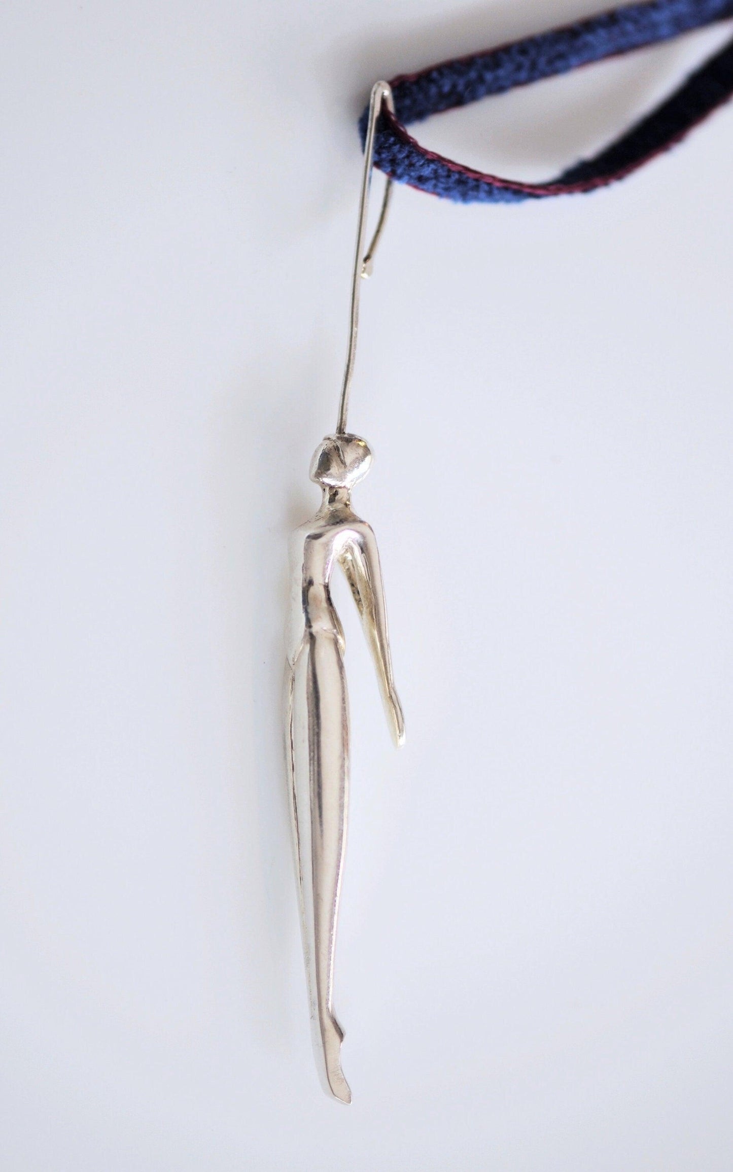 a silver object hanging from a cord on a white surface