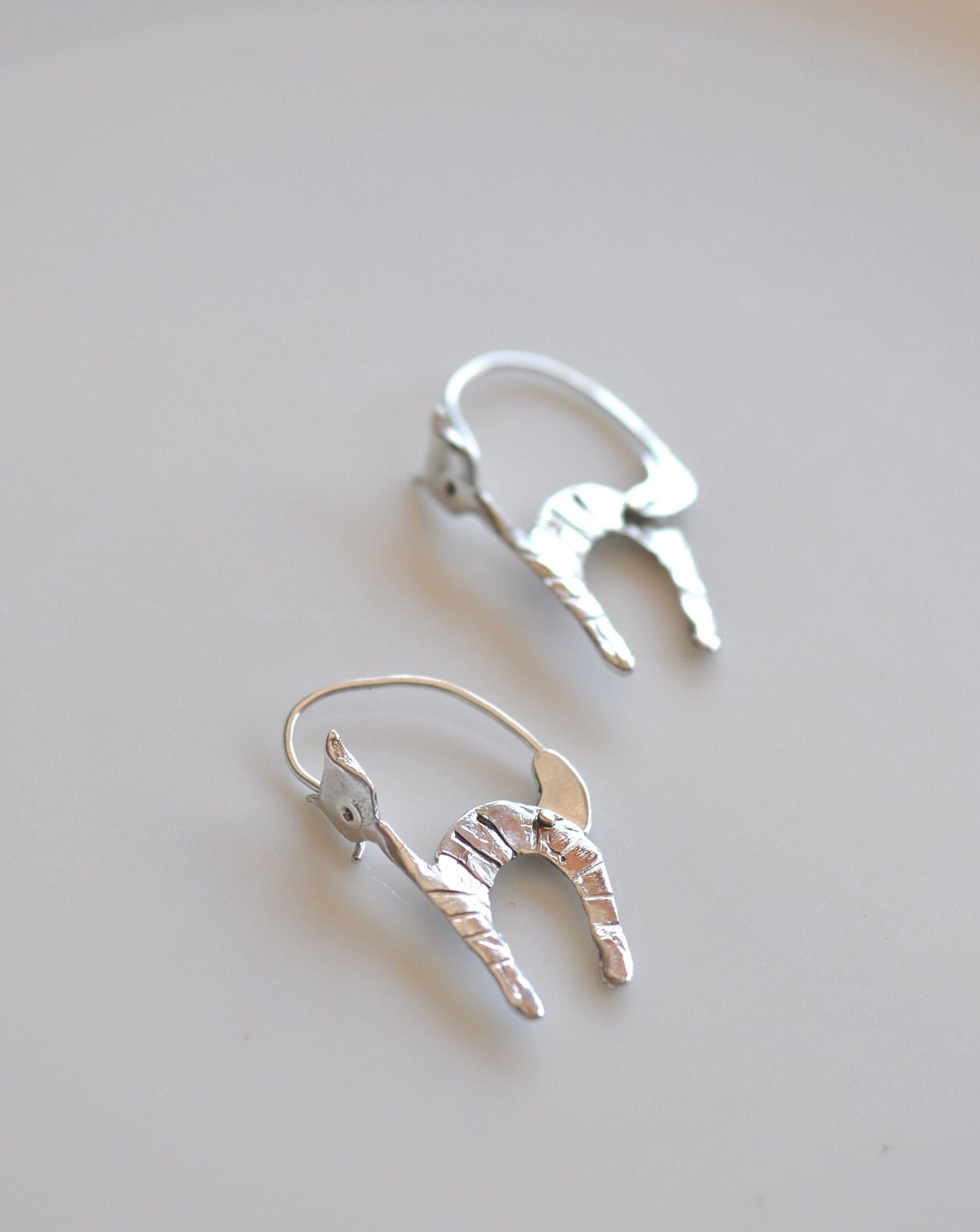 a pair of silver earrings sitting on top of a table