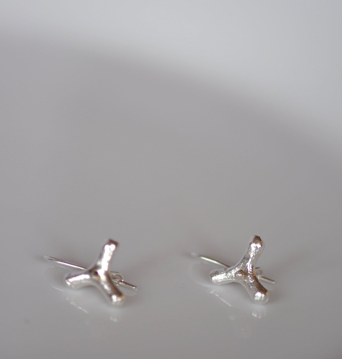 a pair of small silver cross earrings on a white surface