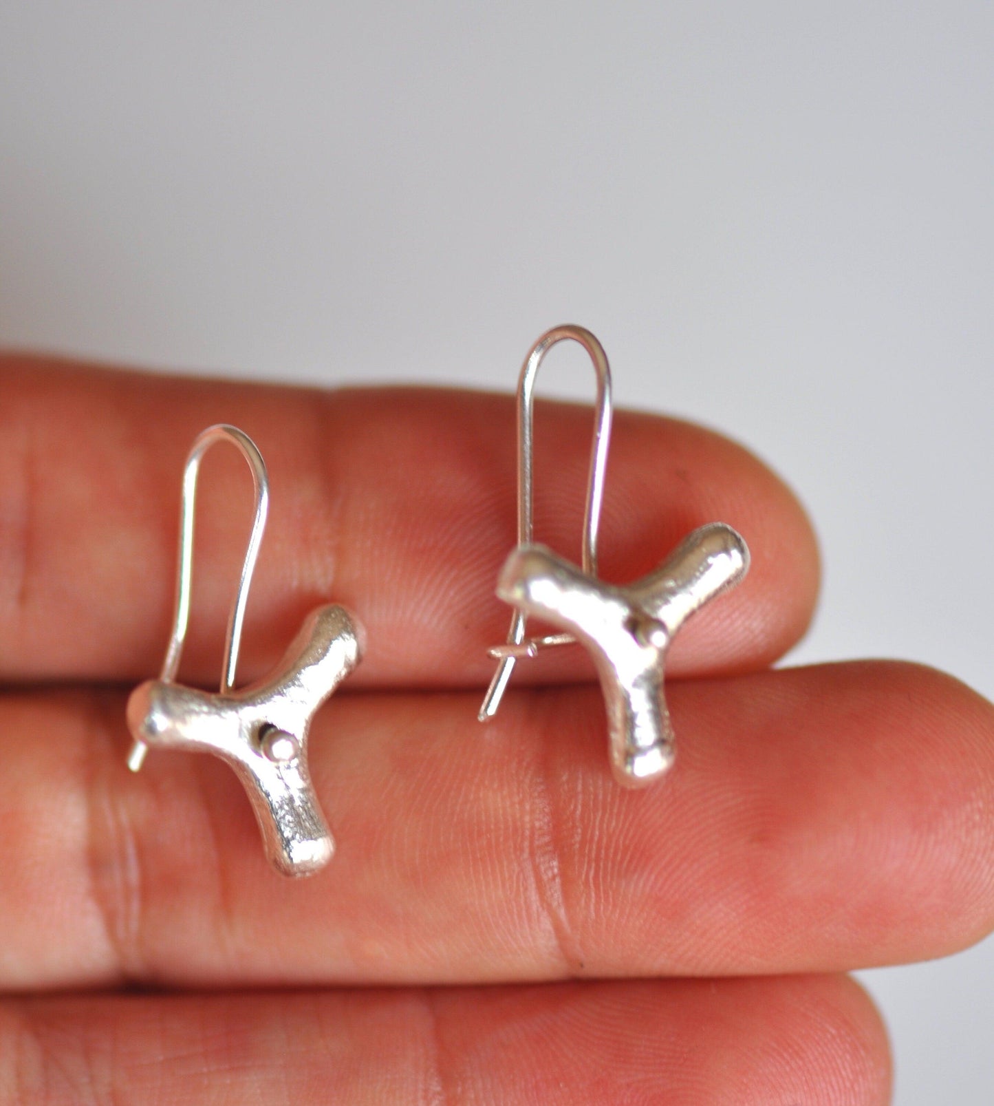 a pair of tiny silver earrings with a dog design