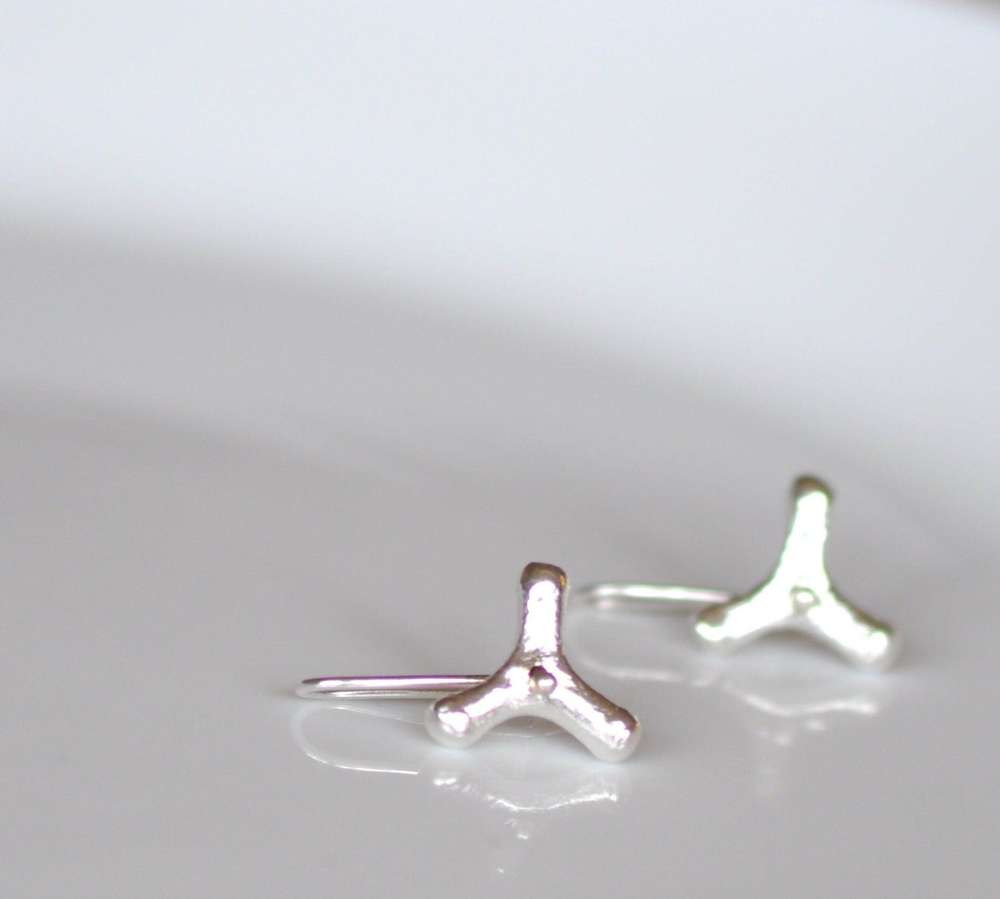 a pair of silver earrings sitting on top of a table